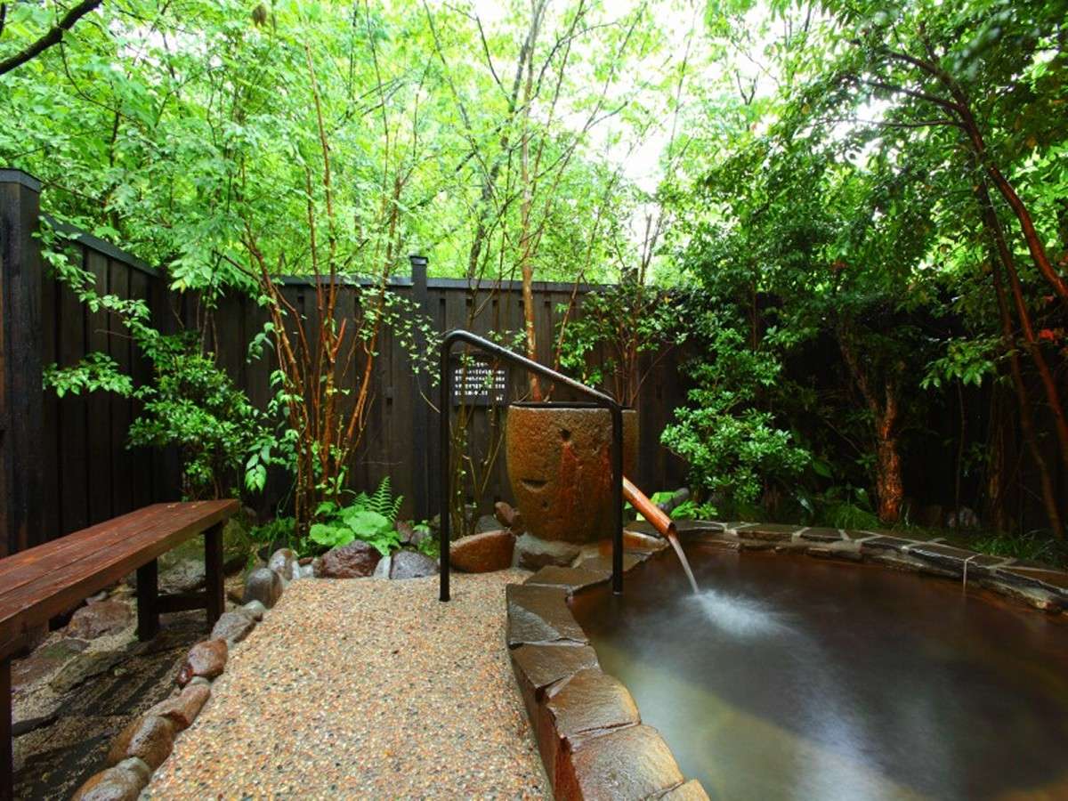 Open-air stone rotenburo at Oyado Nonohana surrounded by bamboo and garden foliage