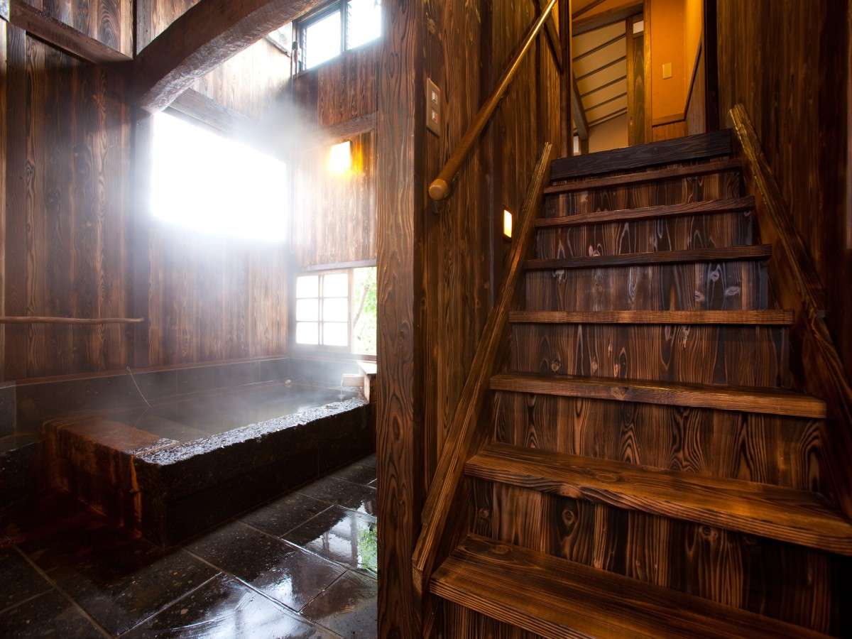 Indoor wooden bath at Oyado Nonohana beside a steep timber staircase