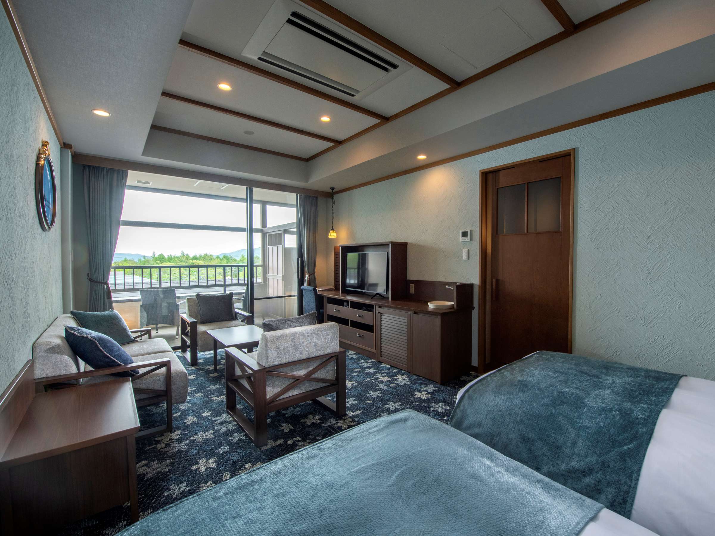 Spacious twin guest room at La Vista Kusatsu Hills in soft blue tones with a sofa lounge and balcony overlooking the mountains
