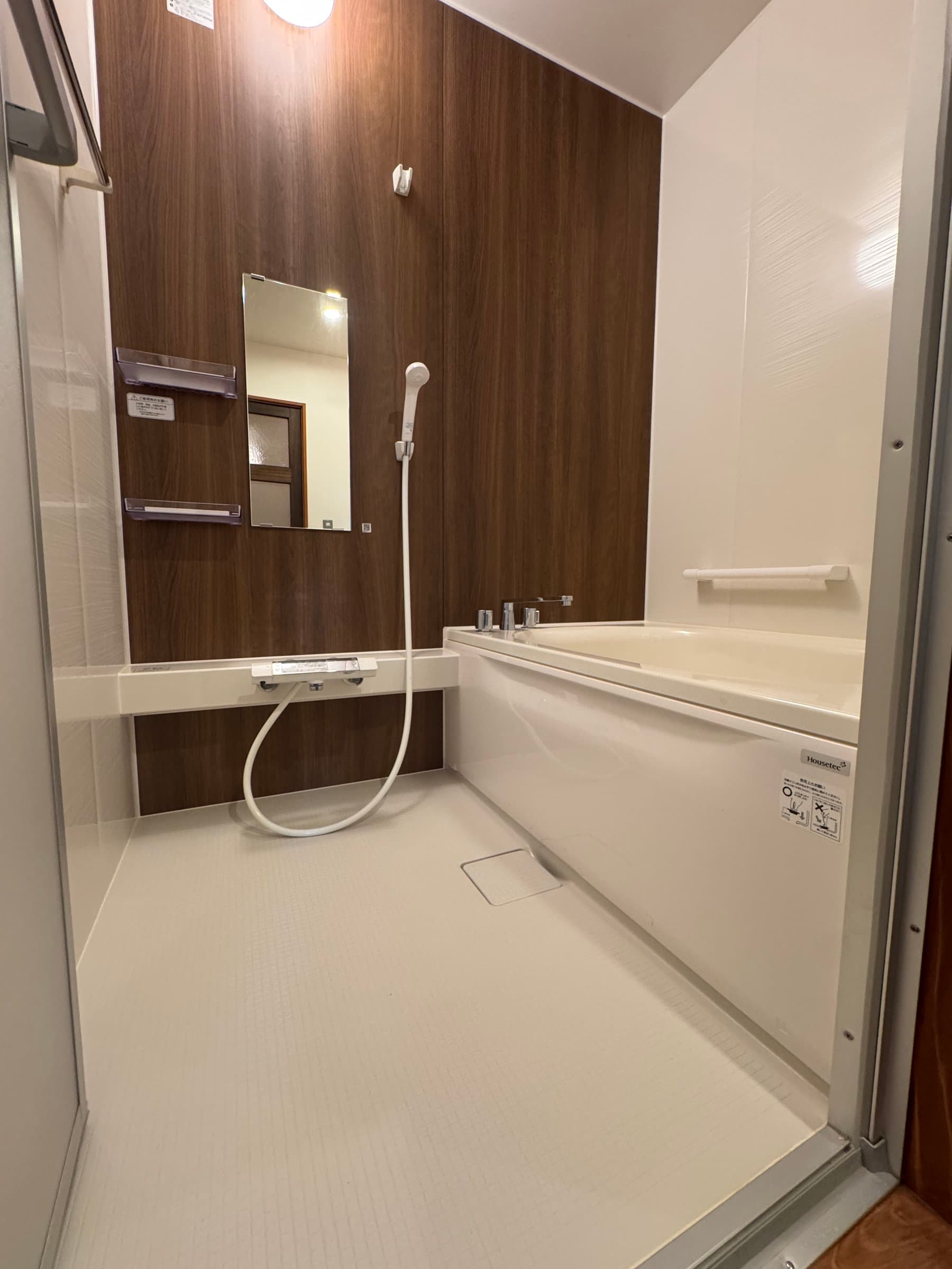 Private guest bathroom with a deep white soaking tub and walnut-panelled wall at Oyado Yanadaya
