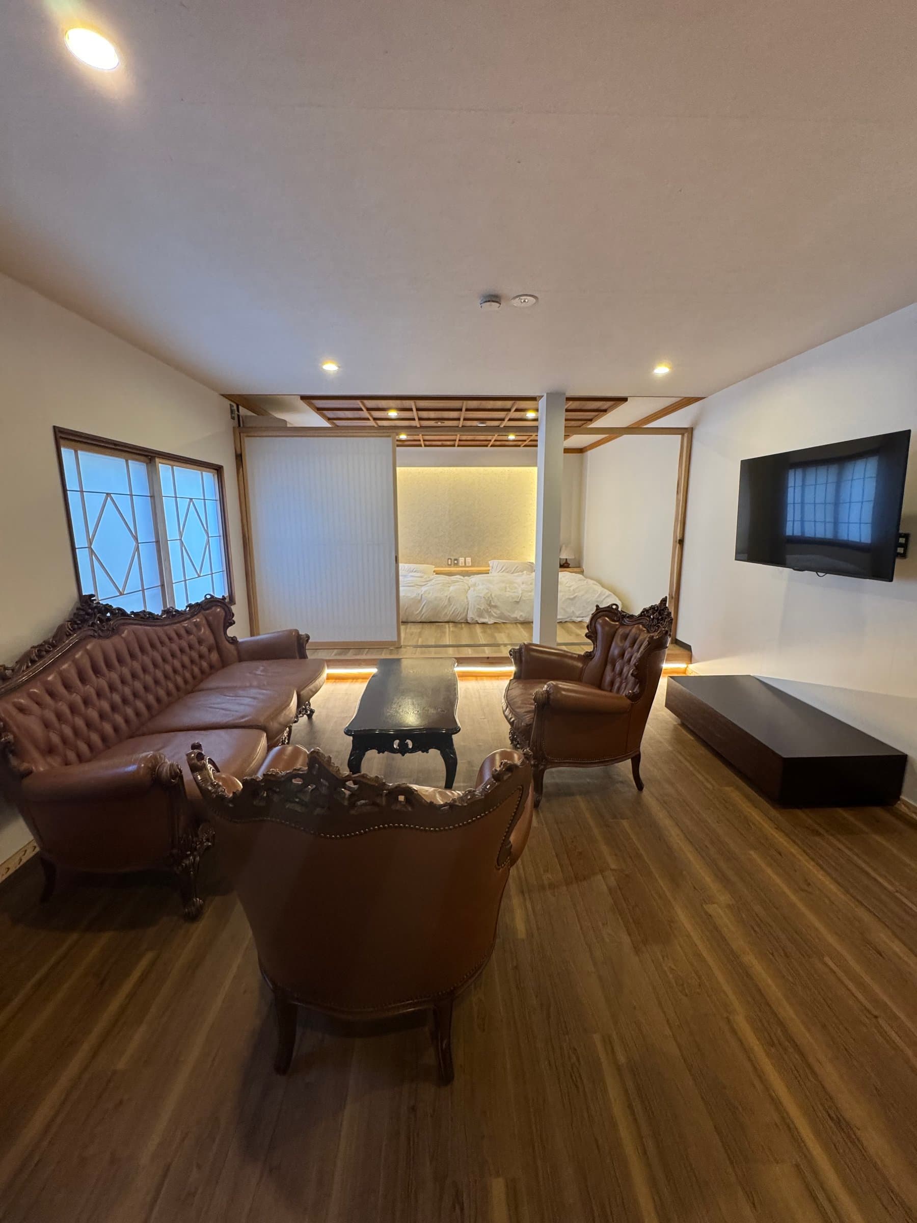 Spacious Western-style sitting room with carved antique leather furniture and an adjoining bedroom at Yanadaya