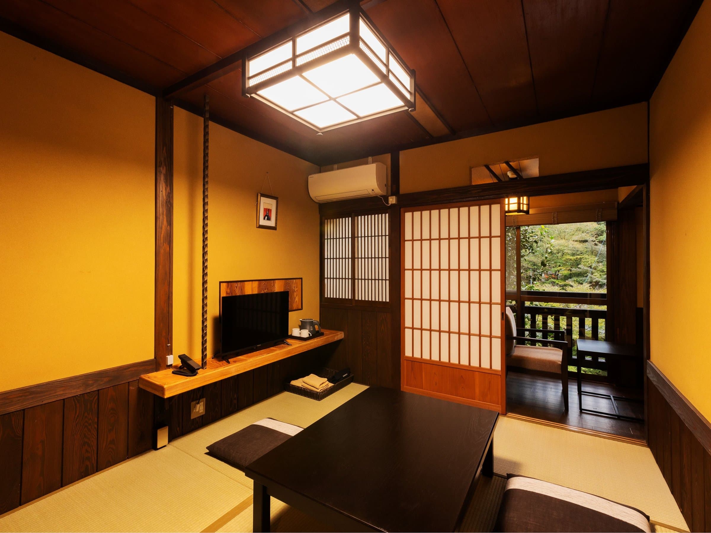 Tatami guest room at Yusai Bekkan with low table, TV console and a shoji-screened balcony facing the garden