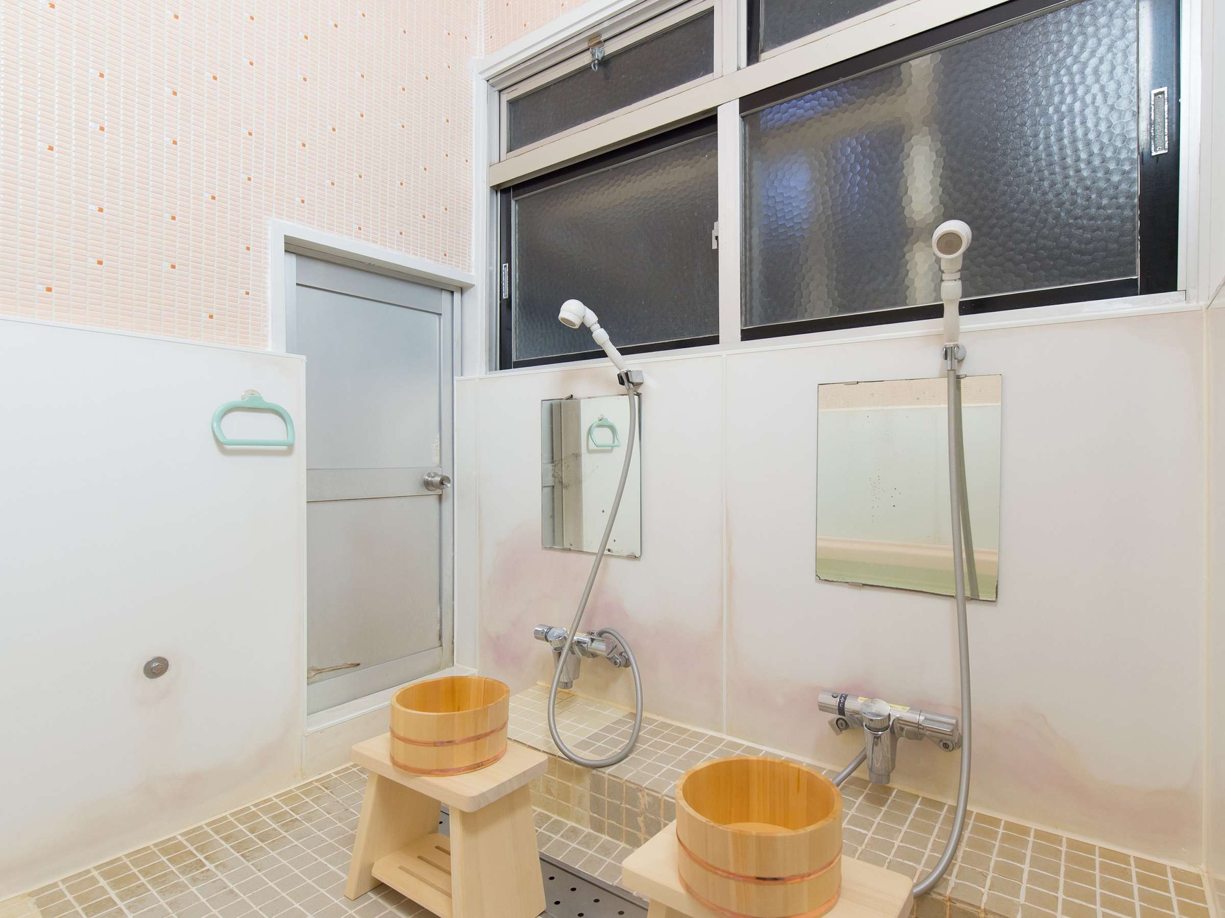 Clean tiled shared bathing room with wooden wash stools and bath buckets at Yamamoto Ryokan