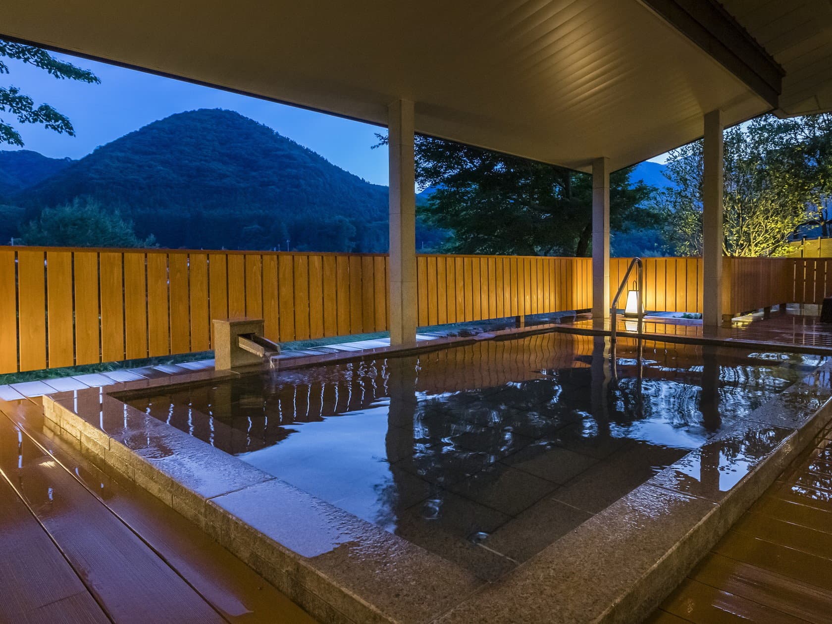 Open-air rotenburo hot spring bath with wooden fence and mountain view at dusk, Wakatake no Sho, Kinugawa Onsen