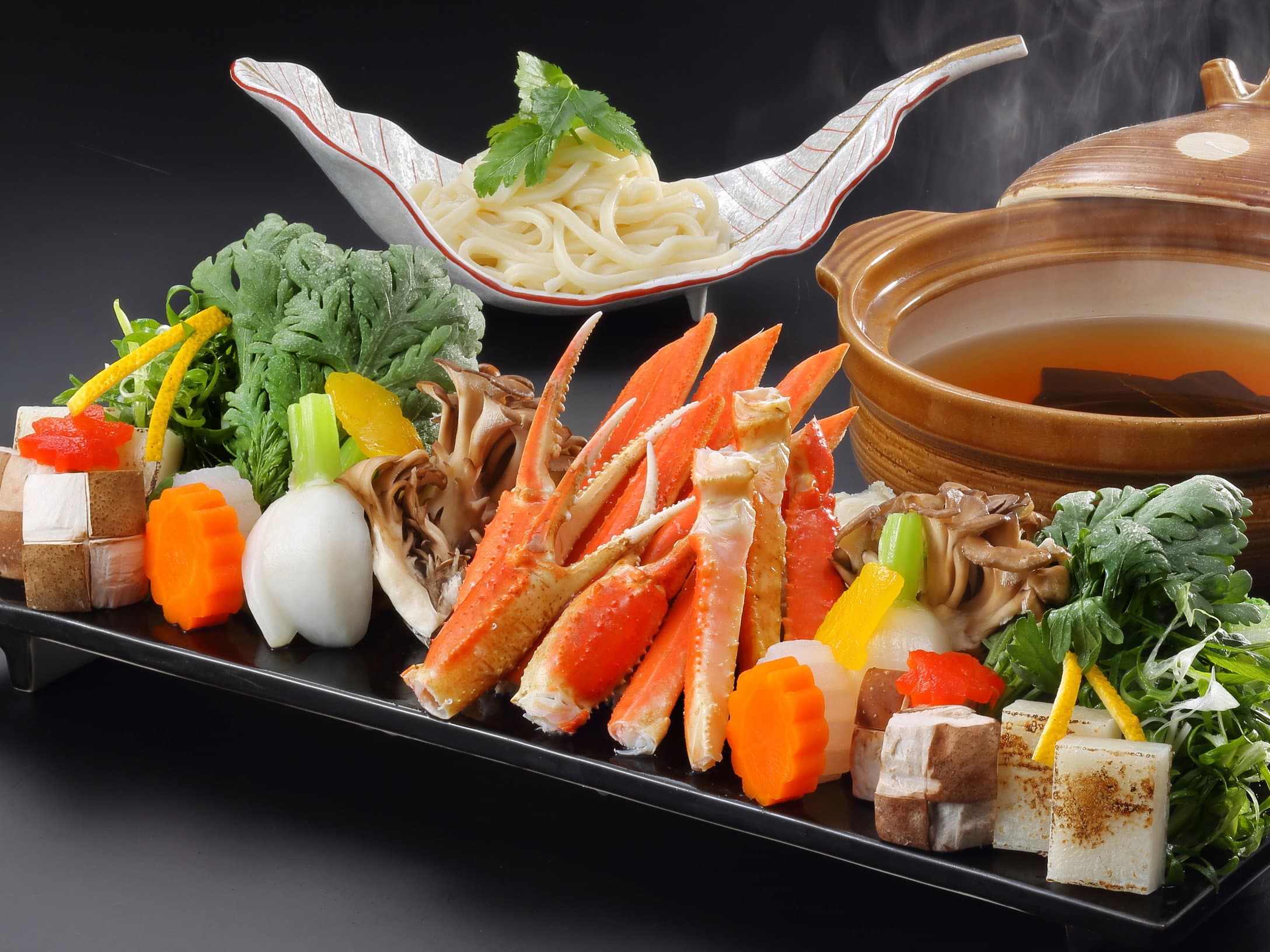 Snow crab hot pot kaiseki dinner set with seasonal vegetables and udon on a black tray at Wakatake no Sho, Nikko