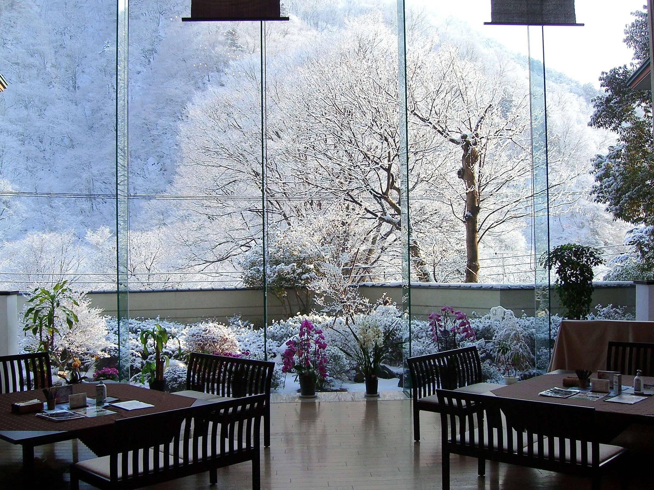 Dining lounge with floor-to-ceiling glass framing a snow-covered garden and mountains at Nikko Senhime Monogatari