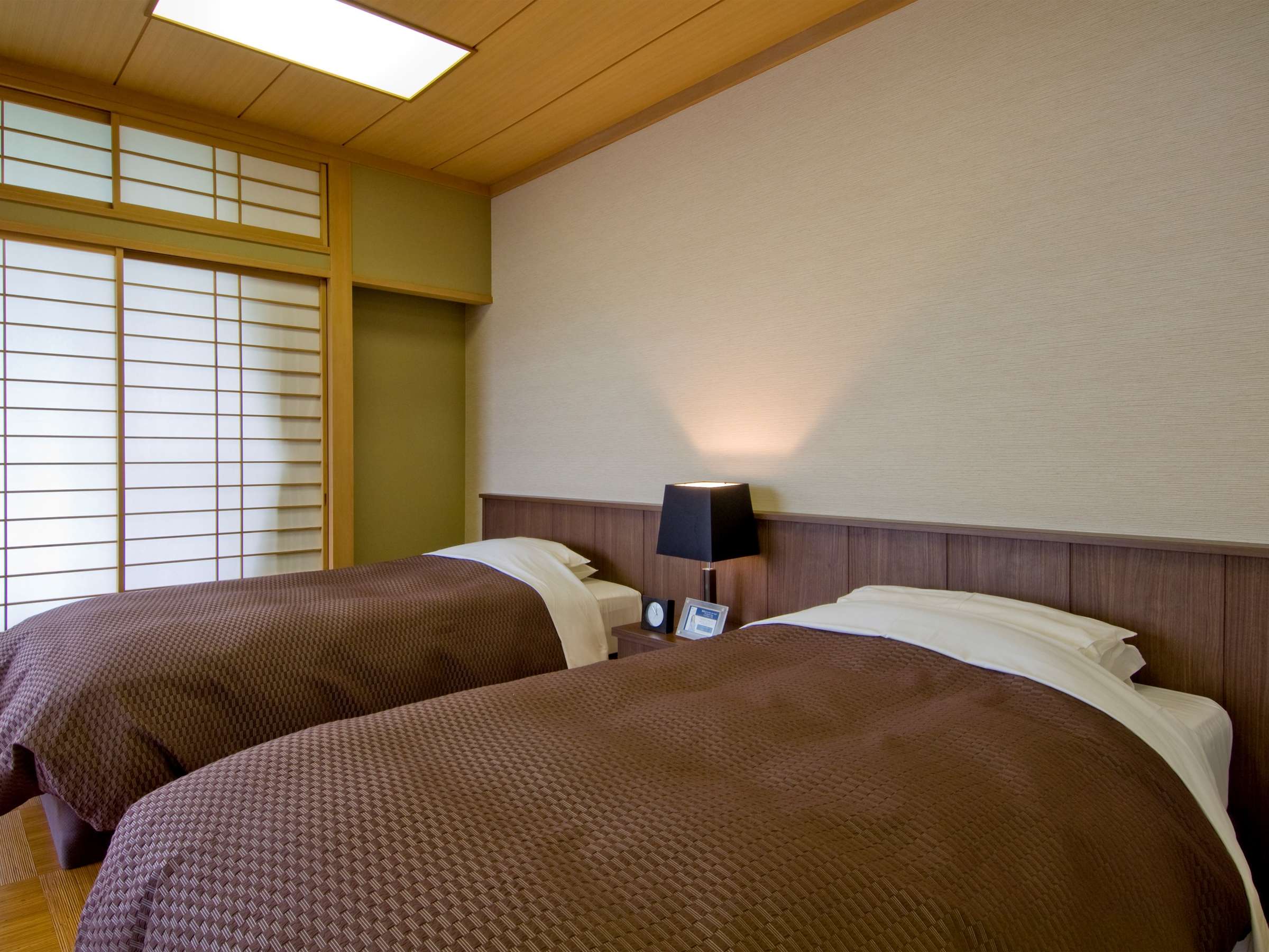 Twin-bed Japanese-Western guest room with shoji screens and warm lamp lighting at Nikko Senhime Monogatari