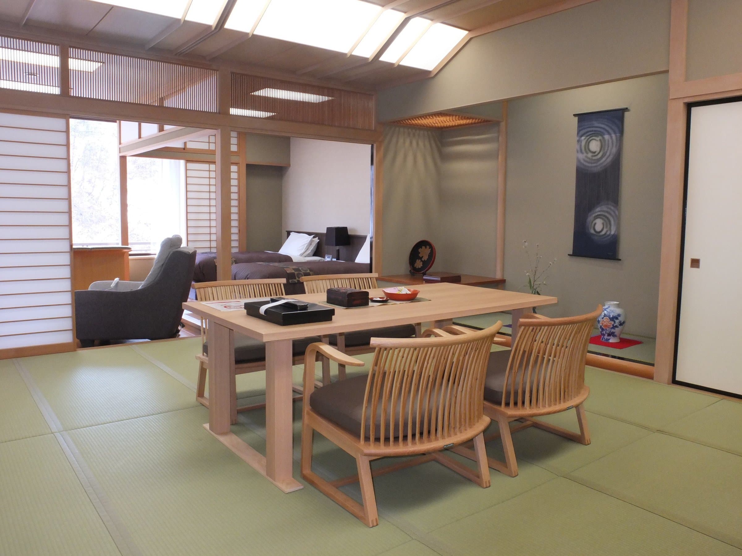 Spacious tatami guest room with wood dining table, armchairs and lounge area at Nikko Senhime Monogatari