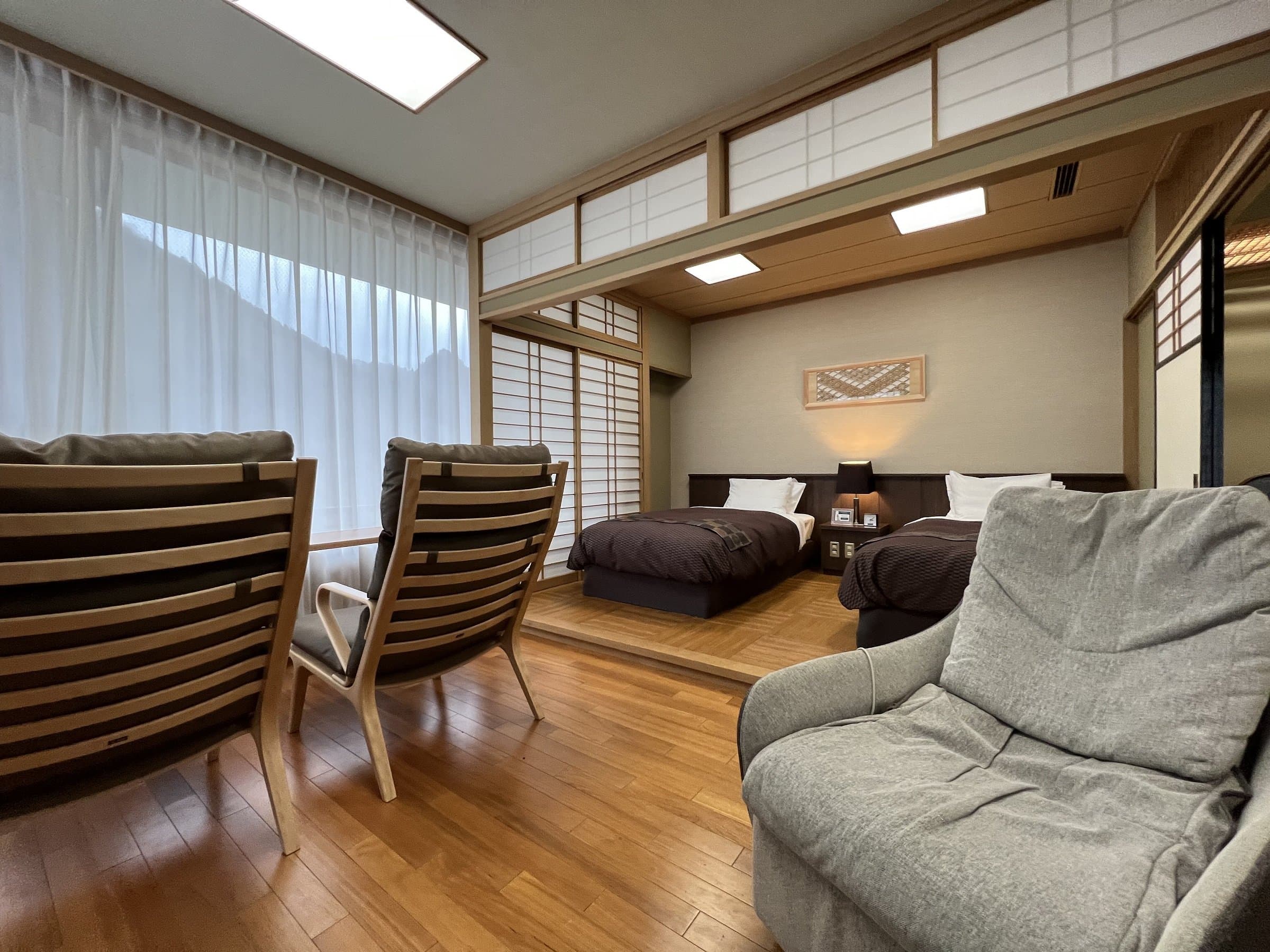 Japanese-style suite with twin beds, sofa and sitting area beneath sheer curtains at Nikko Senhime Monogatari