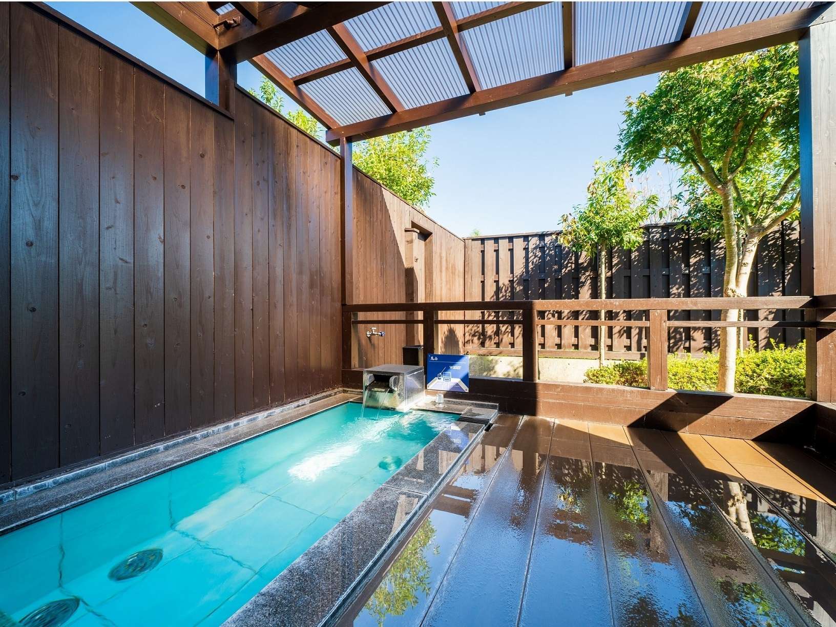 Private open-air stone bath on a wood-walled terrace at Yufuin Hanayoshi in Yufuin Onsen