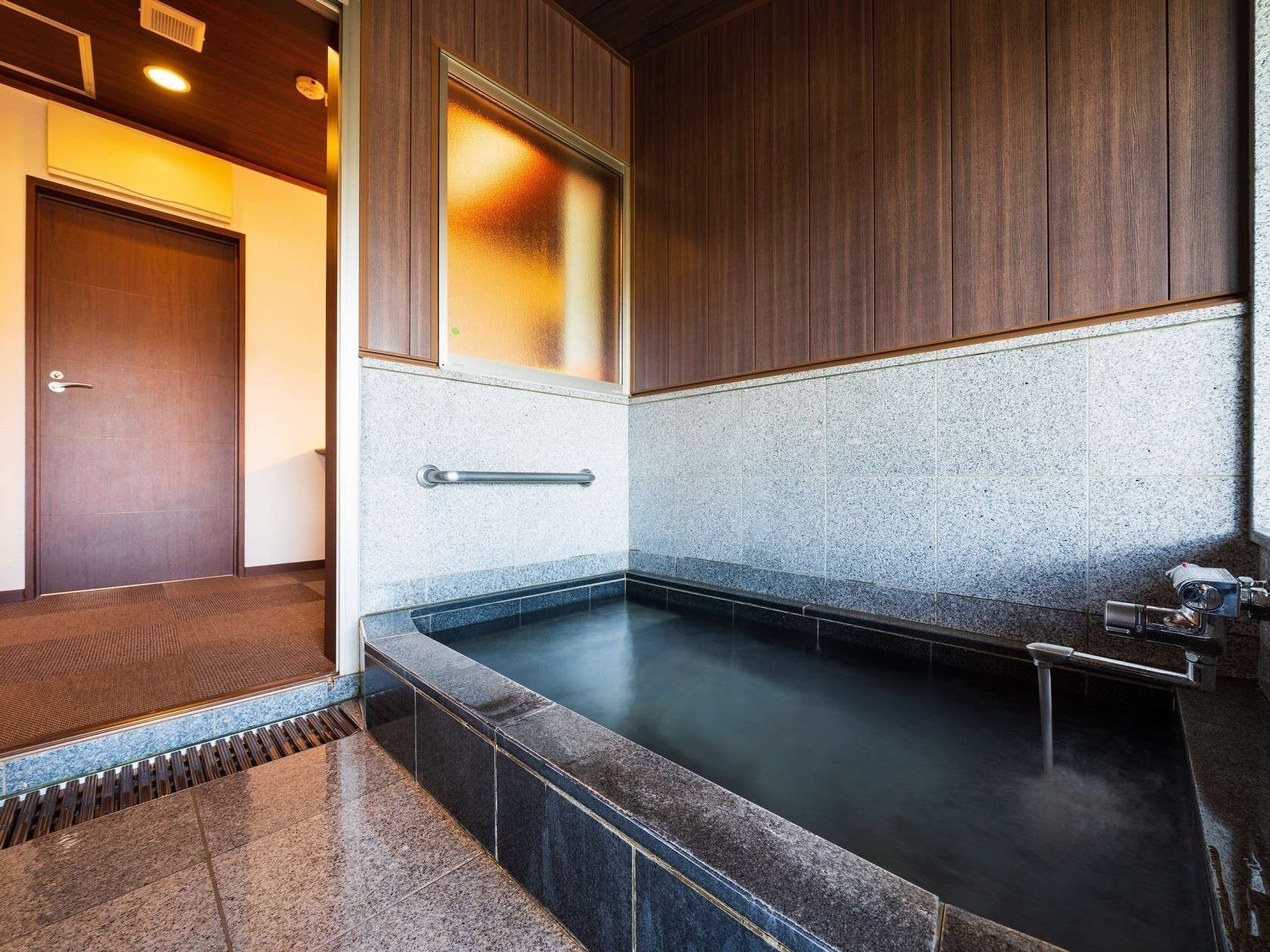 Indoor stone soaking bath with wooden walls in a guest room at Yufuin Hanayoshi