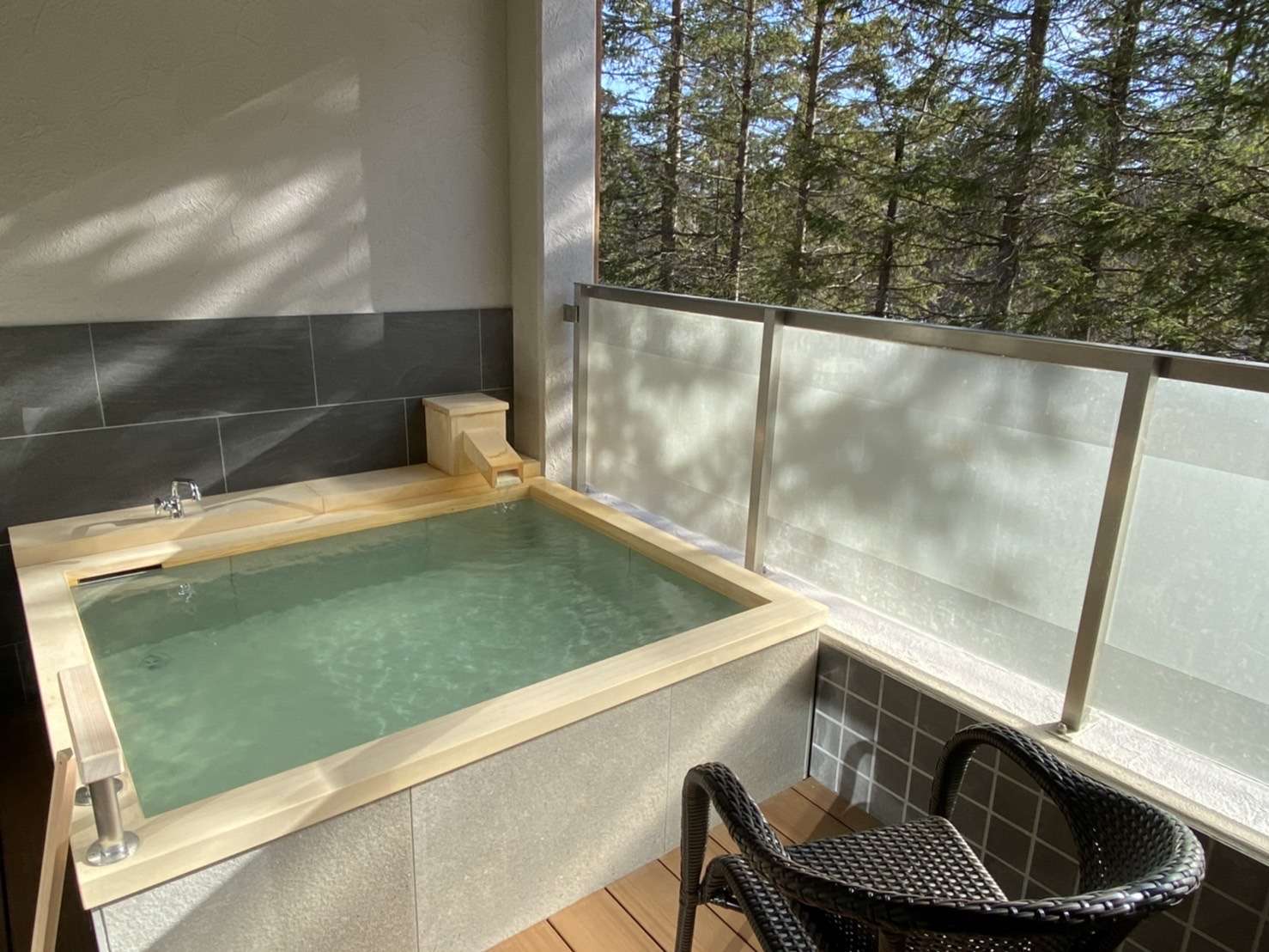 Private open-air hinoki bath on a guest-room balcony overlooking the woods at Okunikko Yuno-mori
