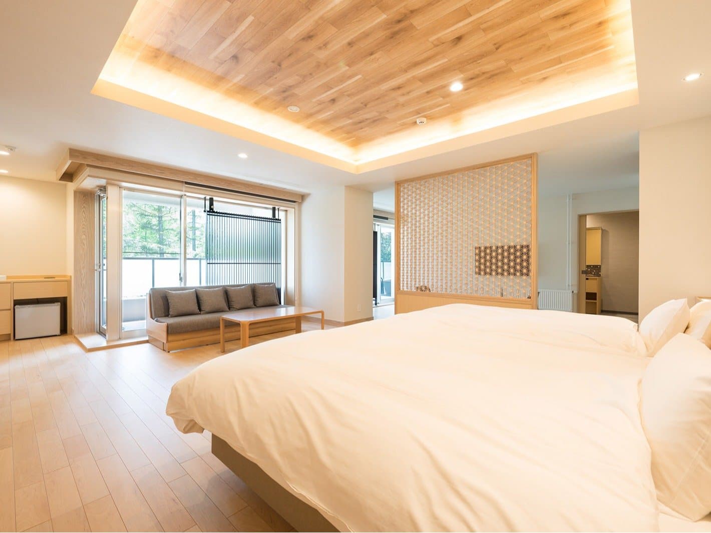 Spacious premium suite bedroom with a large bed, lattice screen and warm wood ceiling at Okunikko Yuno-mori