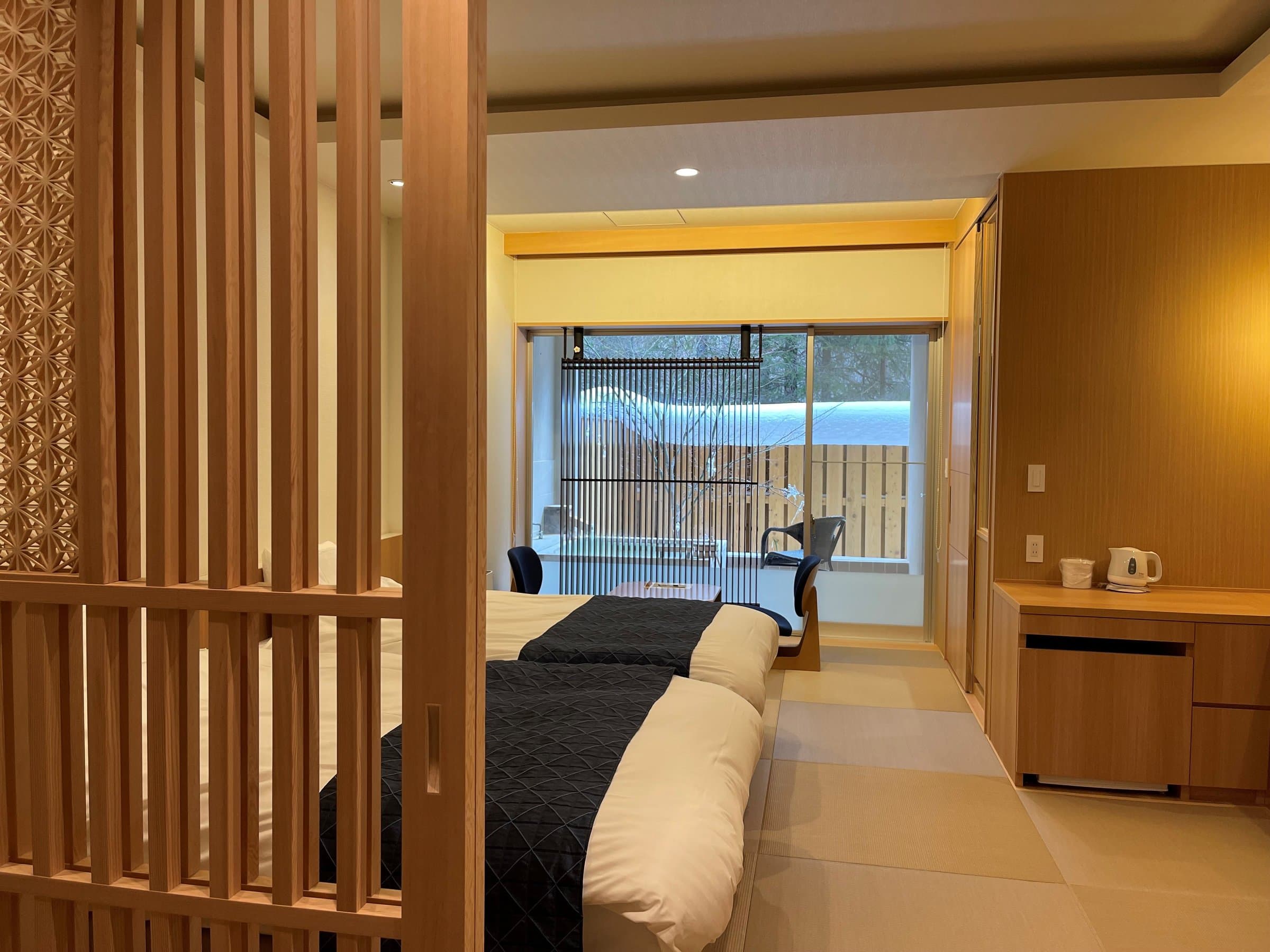 Modern tatami guest room with twin beds opening onto a private open-air bath at Okunikko Yuno-mori
