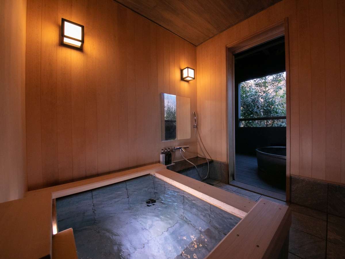 Indoor wooden uchiyu bath in a hinoki-clad room opening to an outdoor tub at Yufuin Bettei Itsuki
