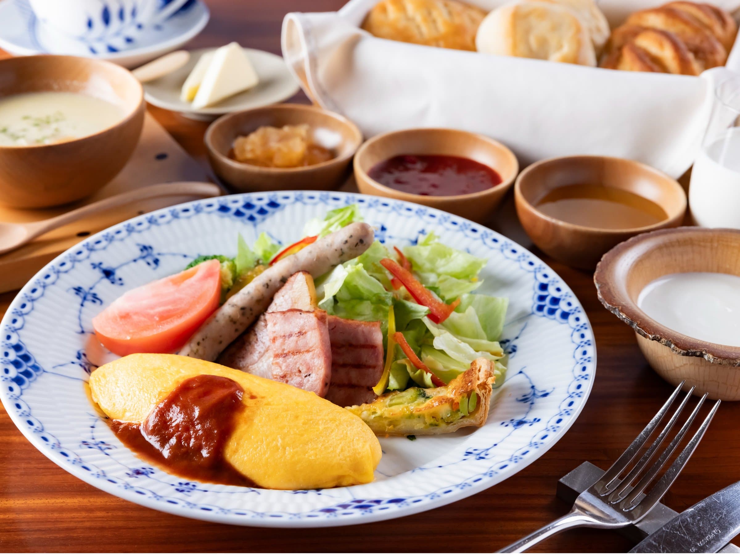 Breakfast plate of omelet, sausage and salad with bread and soup on blue-and-white china at Yufuin Bettei Itsuki