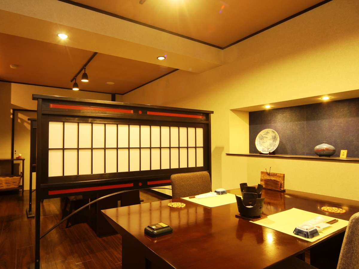 Private dining room with low wooden tables, a lattice shoji screen partition, and a ceramic display alcove