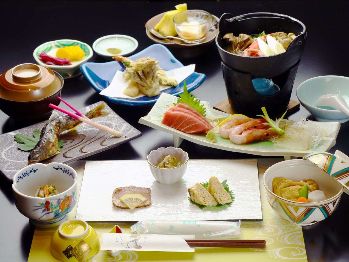 Multi-course kaiseki dinner spread with sashimi, tempura, grilled fish, and a tabletop hot pot