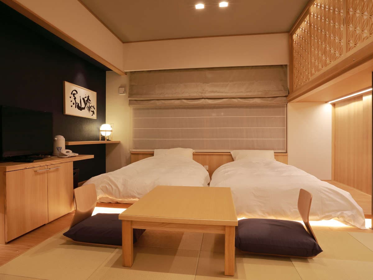 Japanese-style twin-bed guest room on tatami flooring with calligraphy art and warm lighting at Okunikko Kogen Hotel