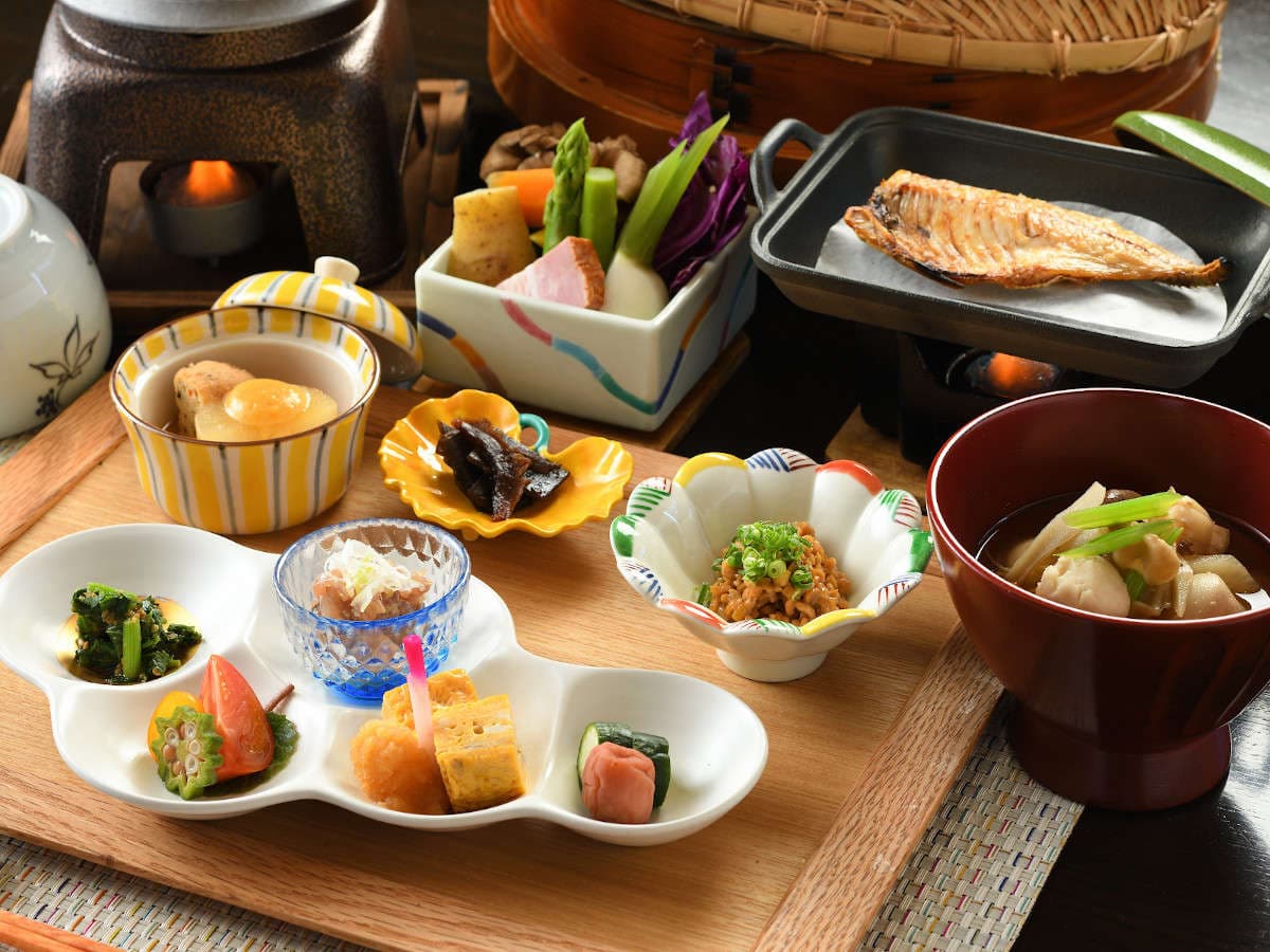 Traditional Japanese breakfast set with grilled fish, simmered dishes and small bowls on a wooden tray at Atagawa Prince Hotel