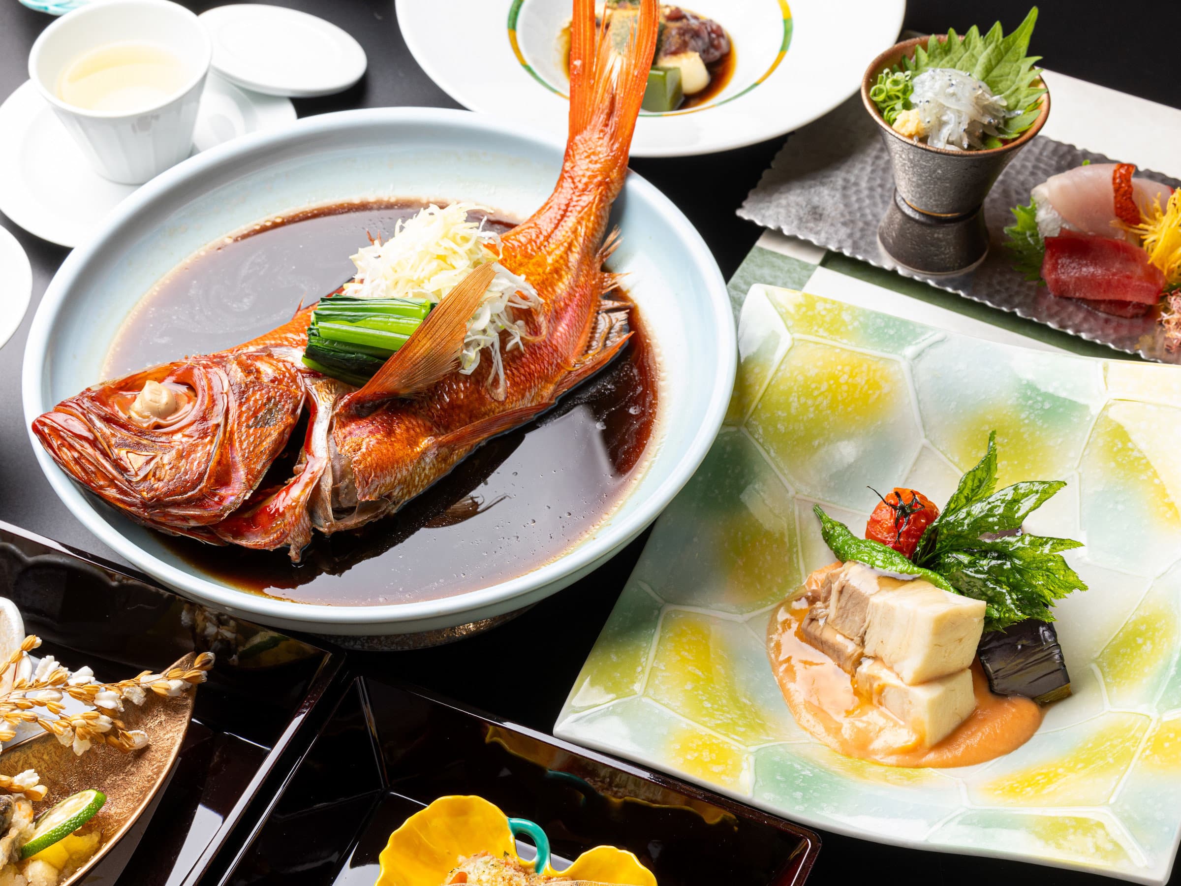 Kaiseki dinner spread featuring simmered local kinmedai (golden eye snapper) and seasonal small dishes at Atagawa Prince Hotel