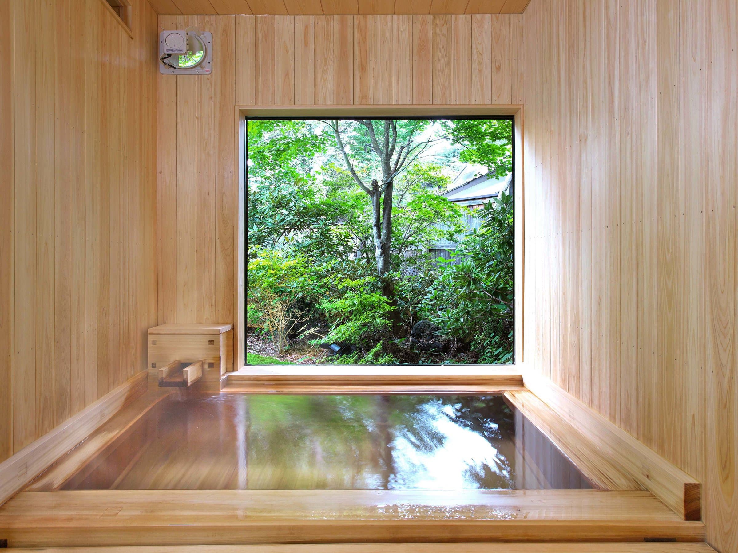 Cypress-wood private bath with a square window framing leafy greenery outside
