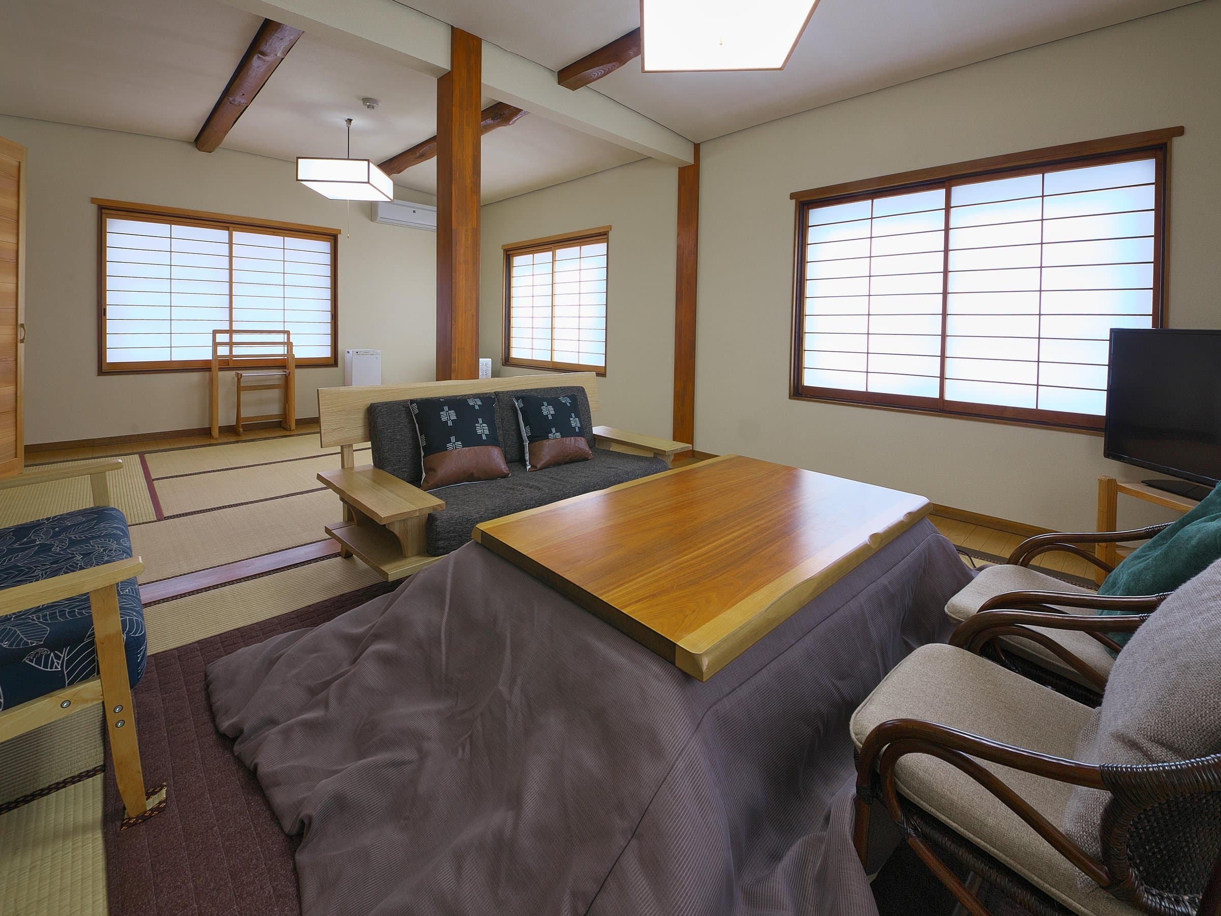 Large Japanese-style room with exposed wood beams, a sunken seating nook and rattan chairs