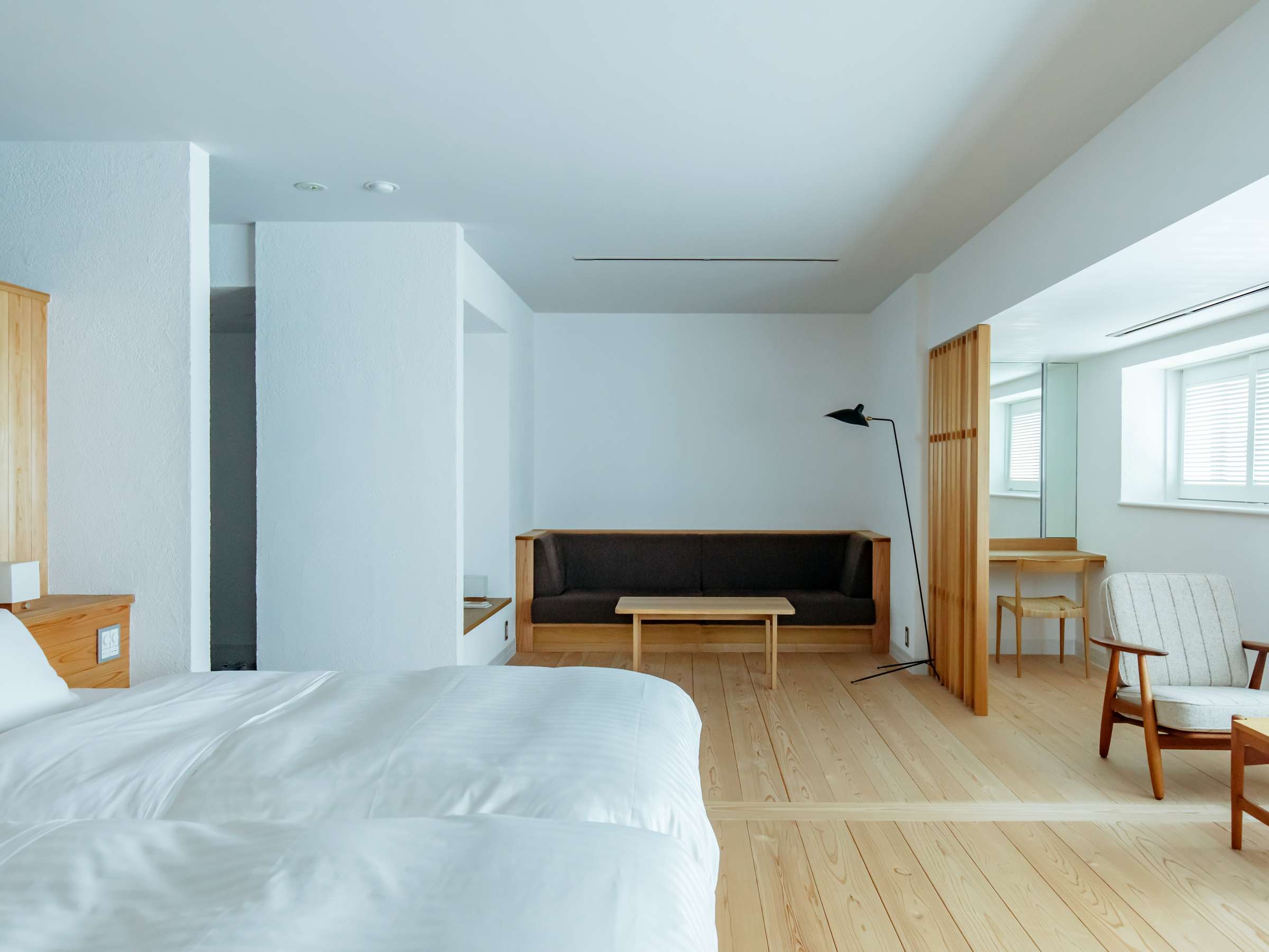 Bright minimalist guest room with white walls, low sofa and pale cedar flooring, Sensui, Kinosaki Onsen