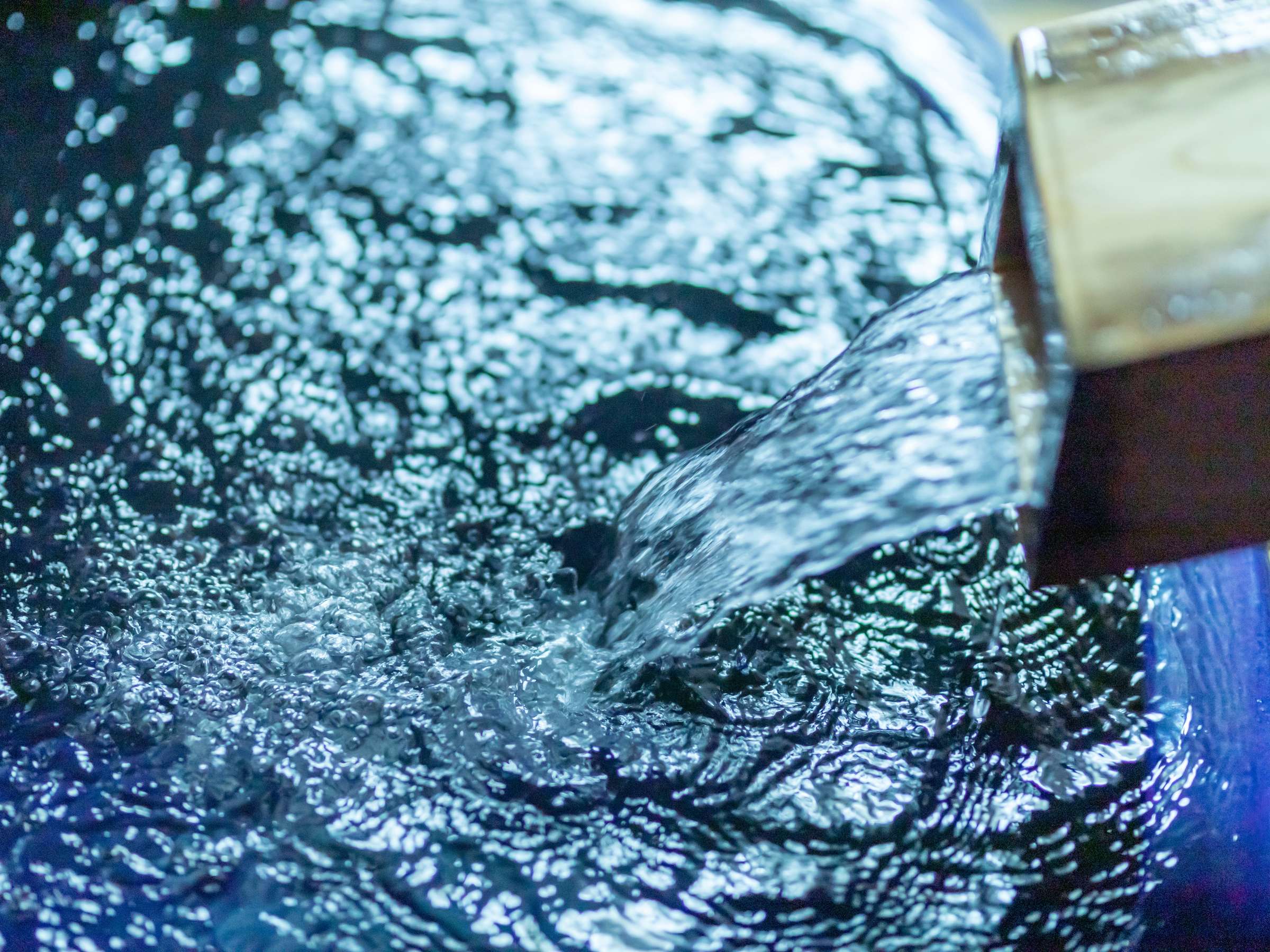 Close-up of hot spring water cascading into a glistening bath surface, Sensui, Kinosaki Onsen