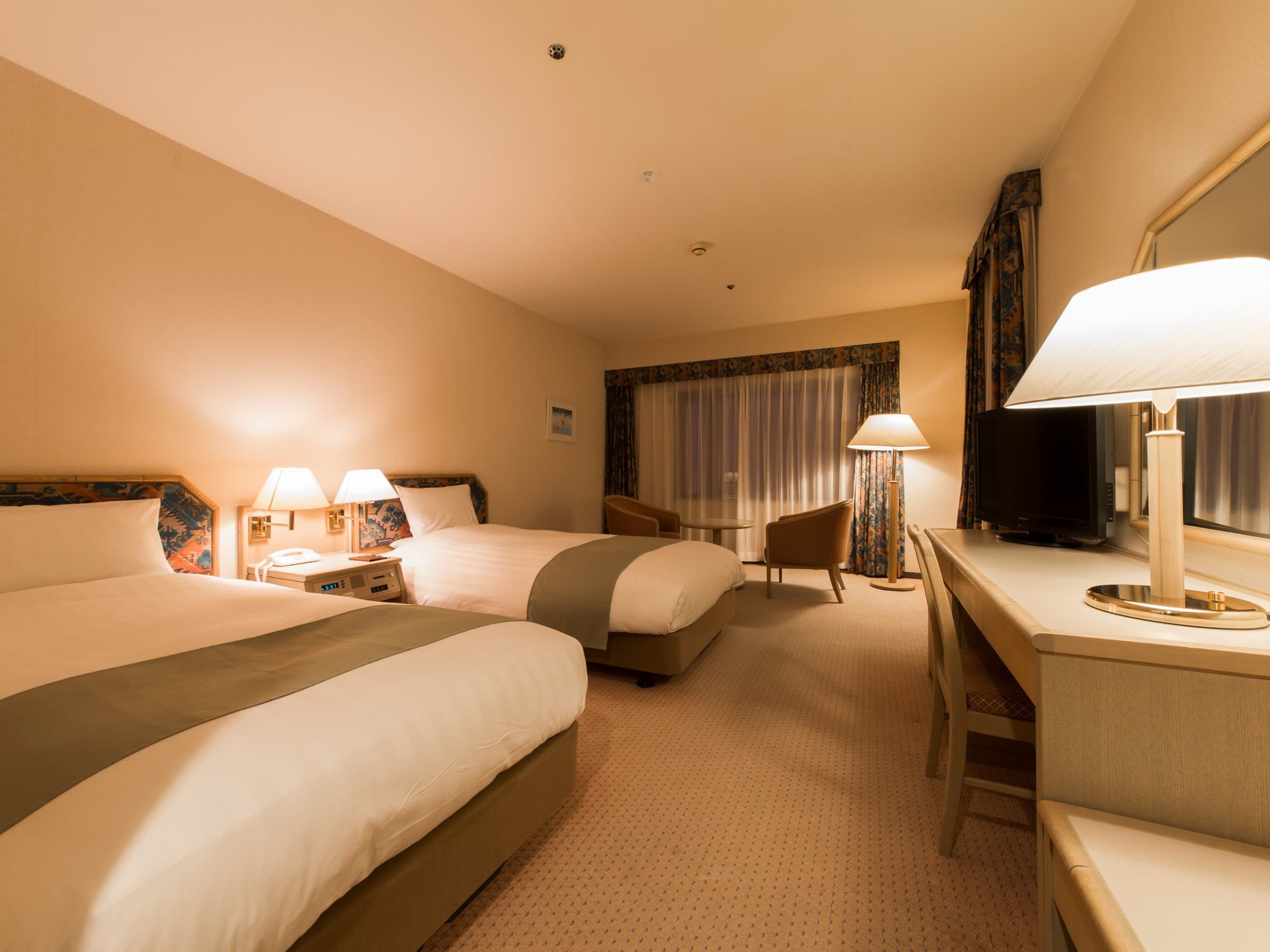 Western-style twin guest room with two beds, lounge chairs and desk