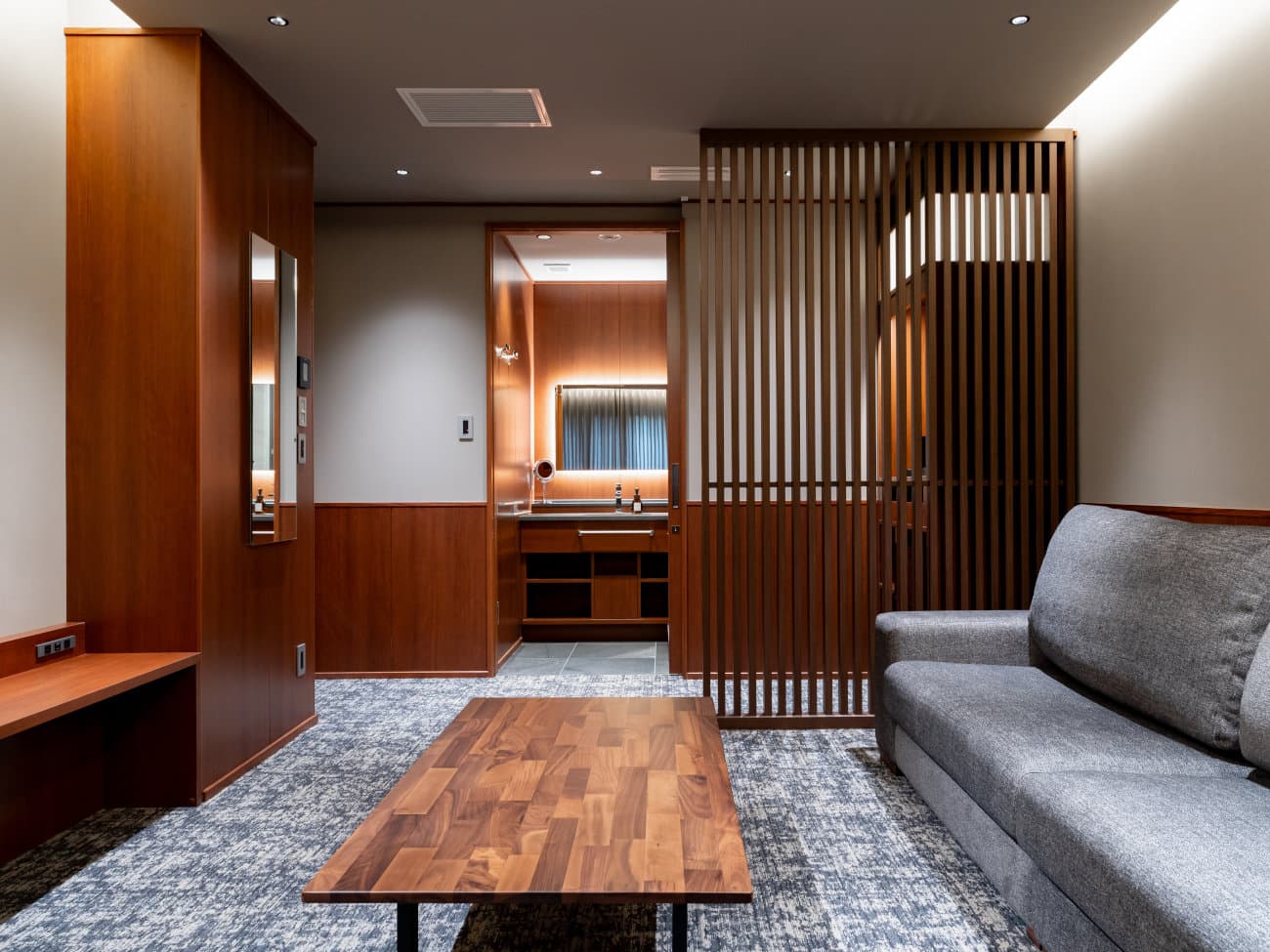 Guest room at Hotel Sierra Resort Hakuba with sofa, low wood table and wood-slat partition by the vanity