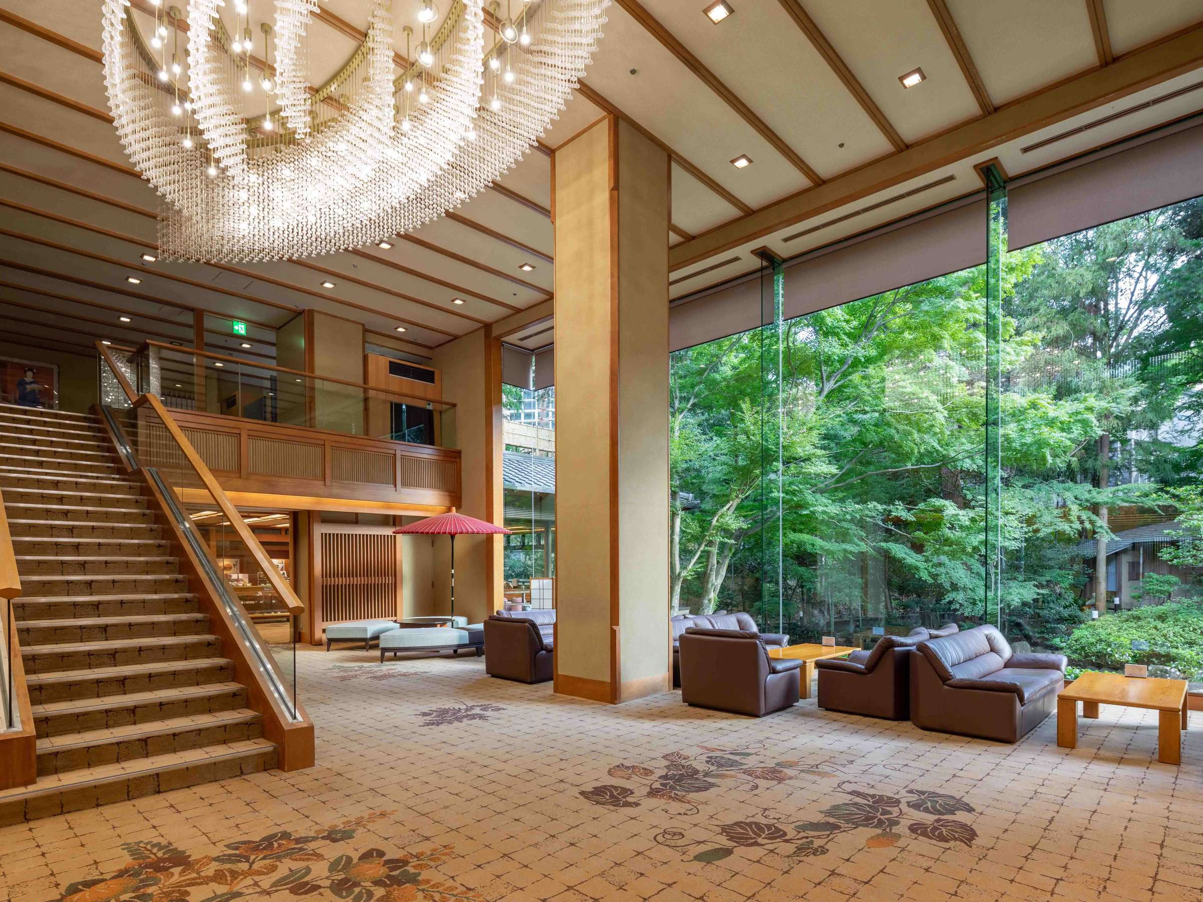Grand lobby lounge with chandelier, staircase and floor-to-ceiling windows onto greenery at Atami Koarashitei