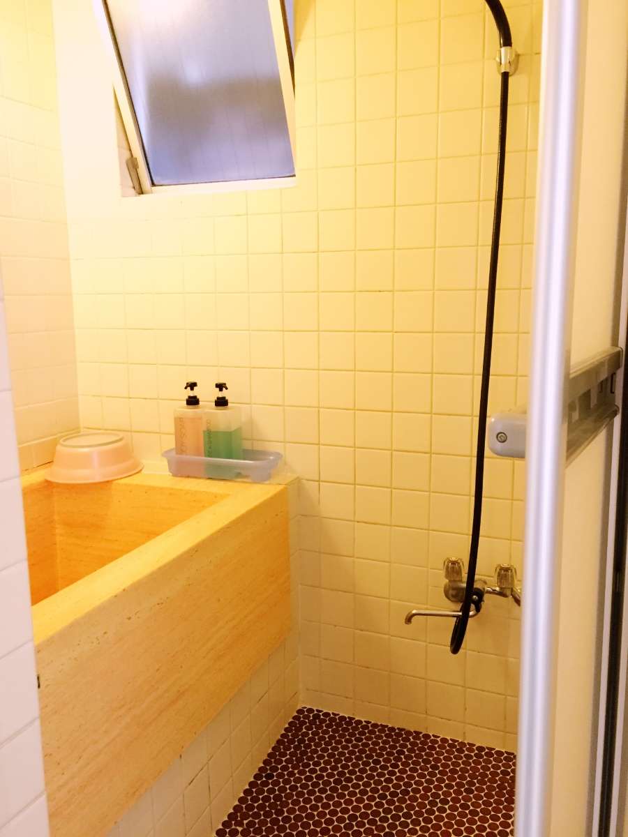Small tiled shower room with a wooden bathtub and toiletries at Asakusa Ryokan Toukaisou