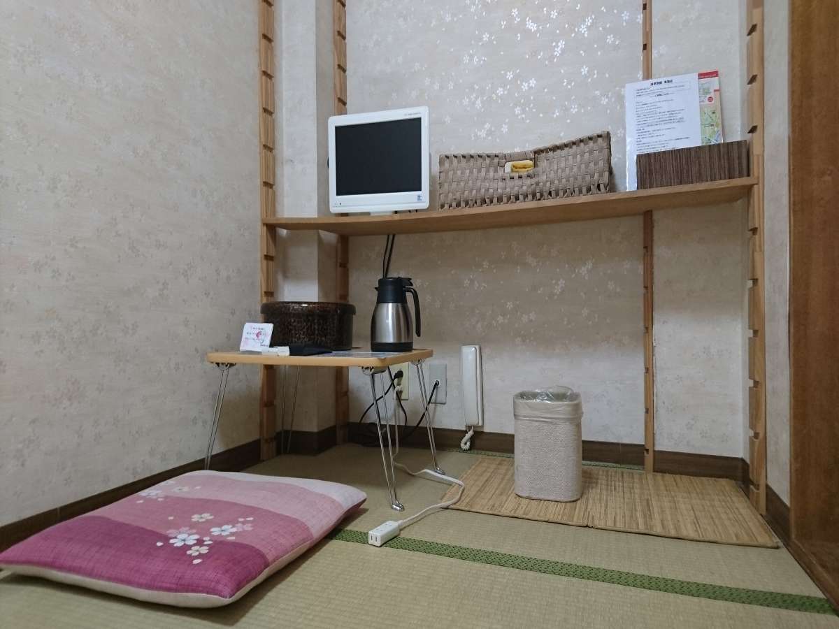 Compact tatami guest room corner at Toukaisou with shelved desk nook, TV and seating cushion