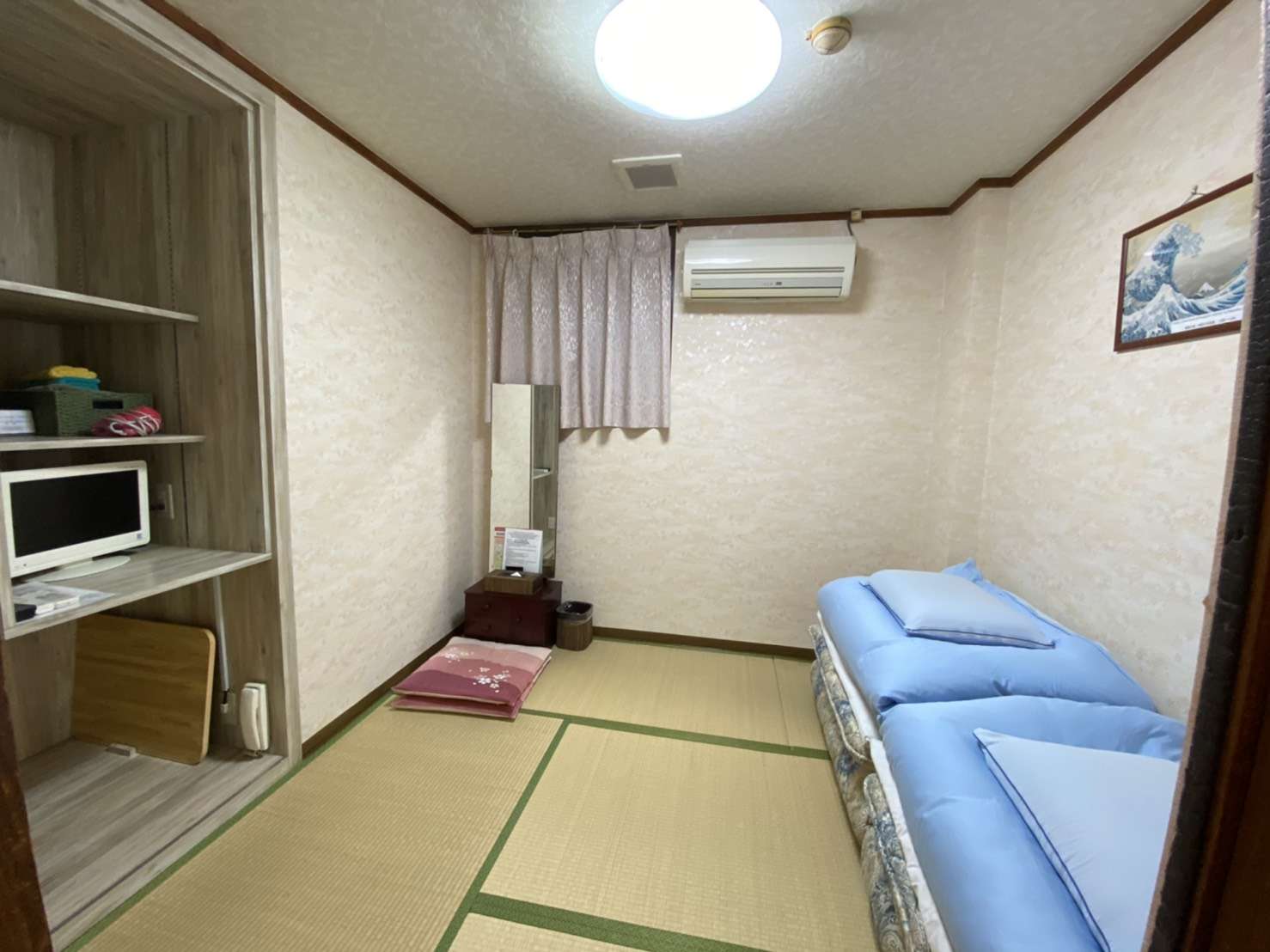 Western-style guest room with a single bed, tatami flooring and a framed Hokusai wave print at Asakusa Toukaisou
