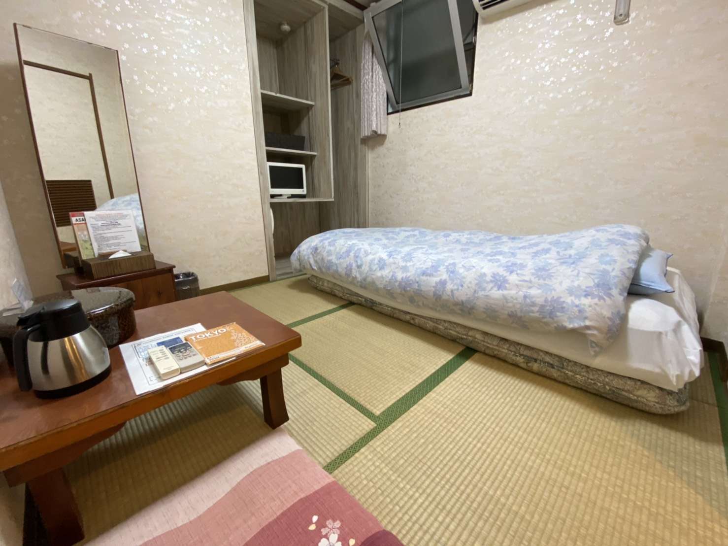 Tatami room at Toukaisou with a low single bed, mirror dresser, tea table and wall-mounted TV