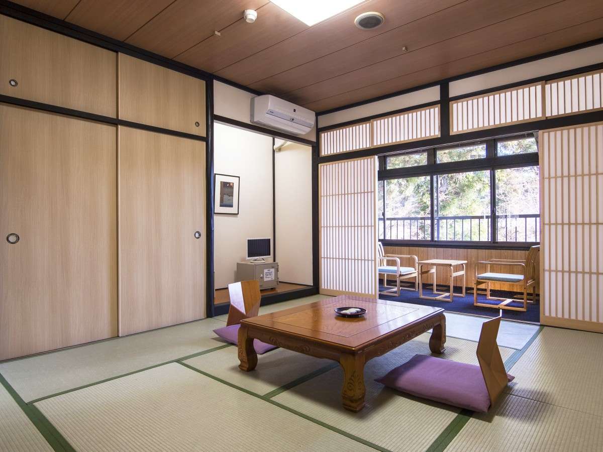 Traditional tatami room at Nikko Tokanso with low lacquer table, floor cushions and shoji screens framing a woodland view