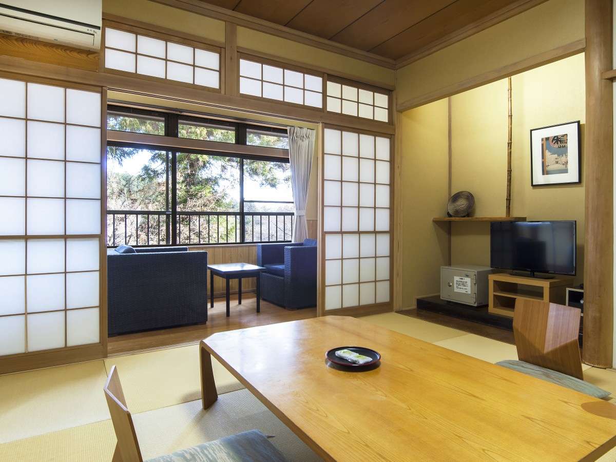 Japanese-style room at Nikko Tokanso with low table, tokonoma display and rattan chairs in a sunlit window nook