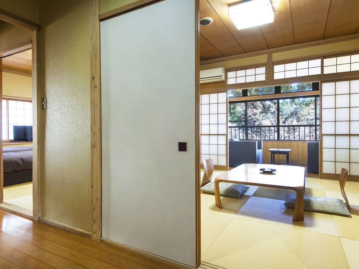 Connecting two-room tatami suite at Nikko Tokanso with sliding fusuma doors and a veranda overlooking trees