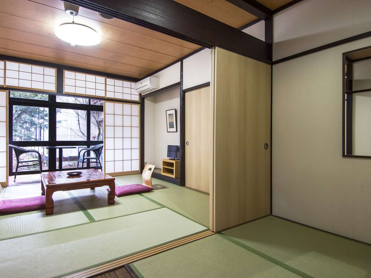 Bright shoji-lit tatami room at Nikko Tokanso with a low table and floor cushions near a wall of paper-screen windows