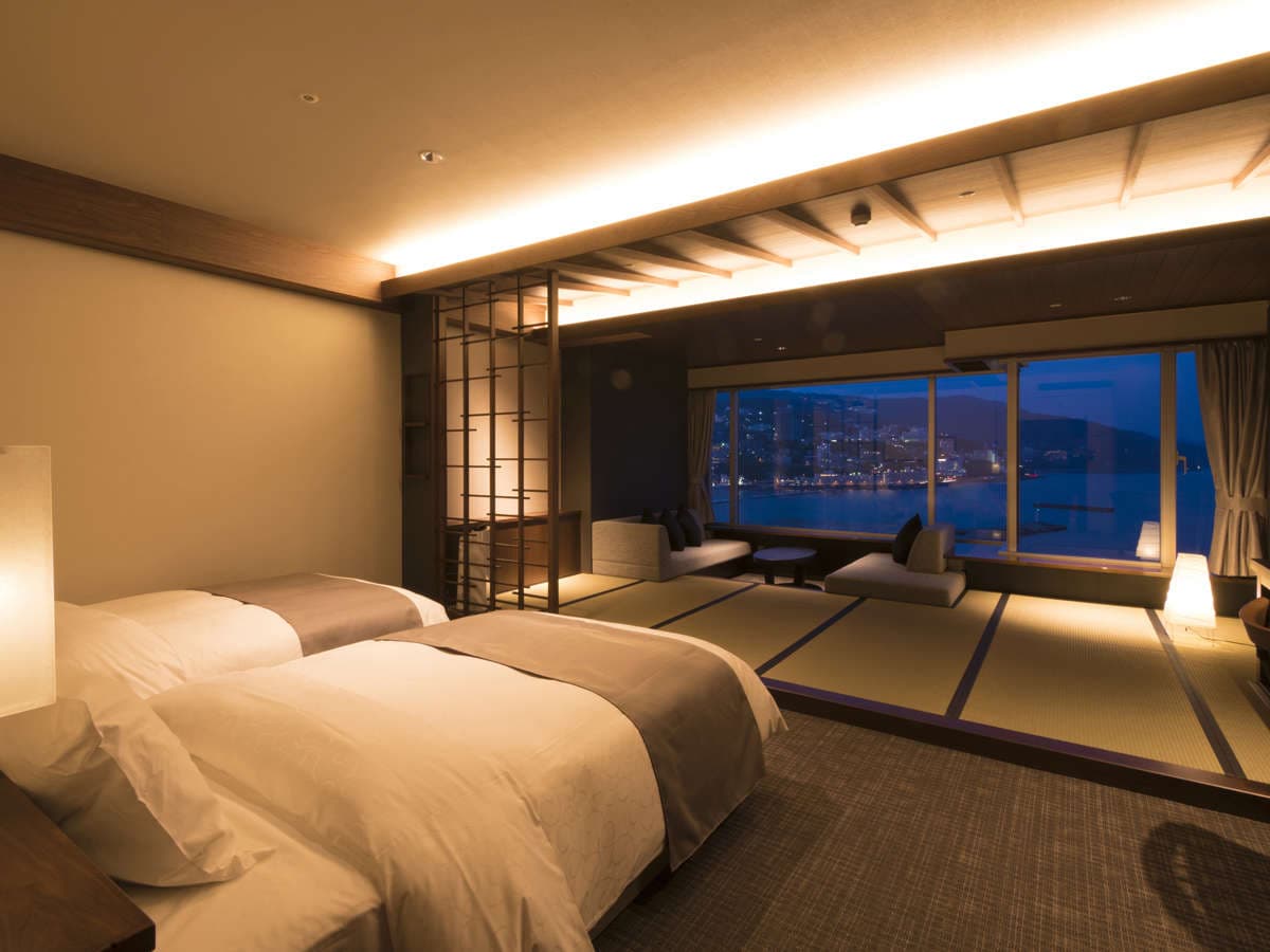 Modern Japanese-style twin guest room with futon beds facing Atami bay at night