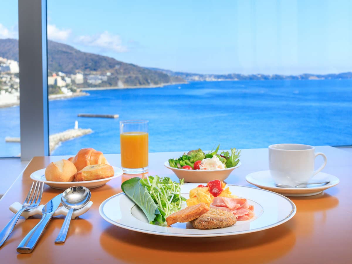 Japanese breakfast set on a table beside a window with bright Atami ocean view