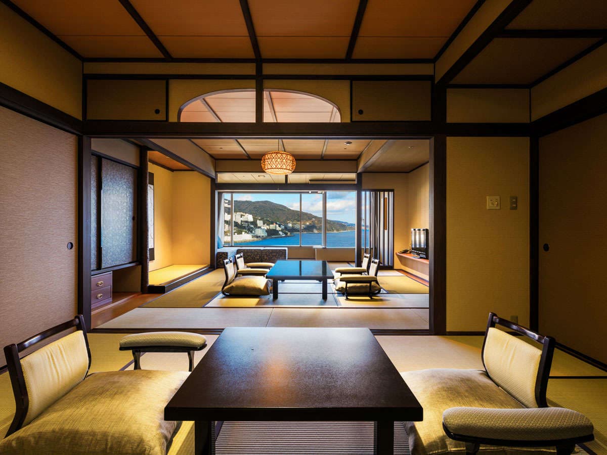 Traditional tatami guest room with low table and panoramic Atami sea view through wide windows
