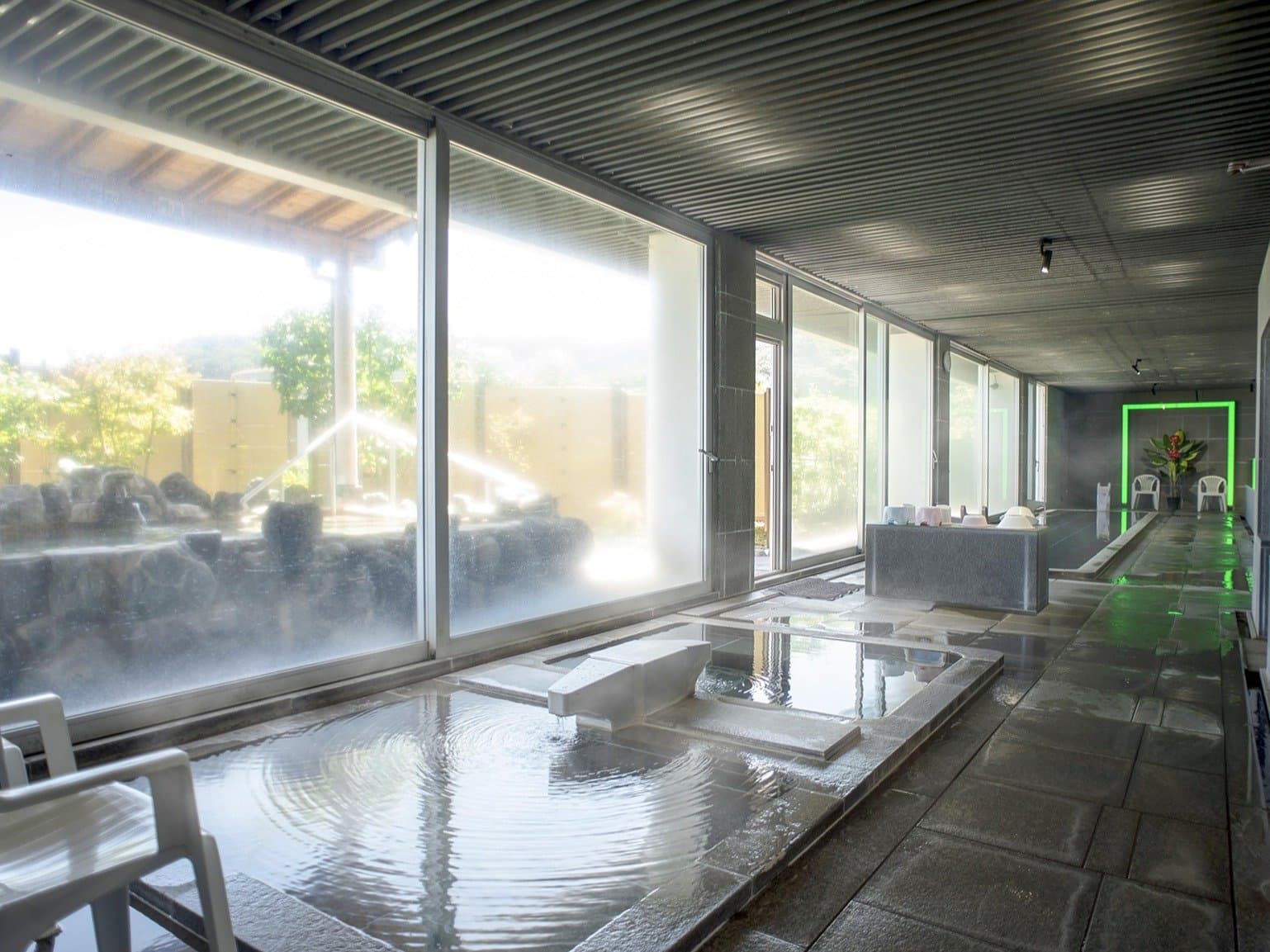 Indoor public bath with floor-to-ceiling windows and stone tubs viewing the garden, Hotel Katara Izu