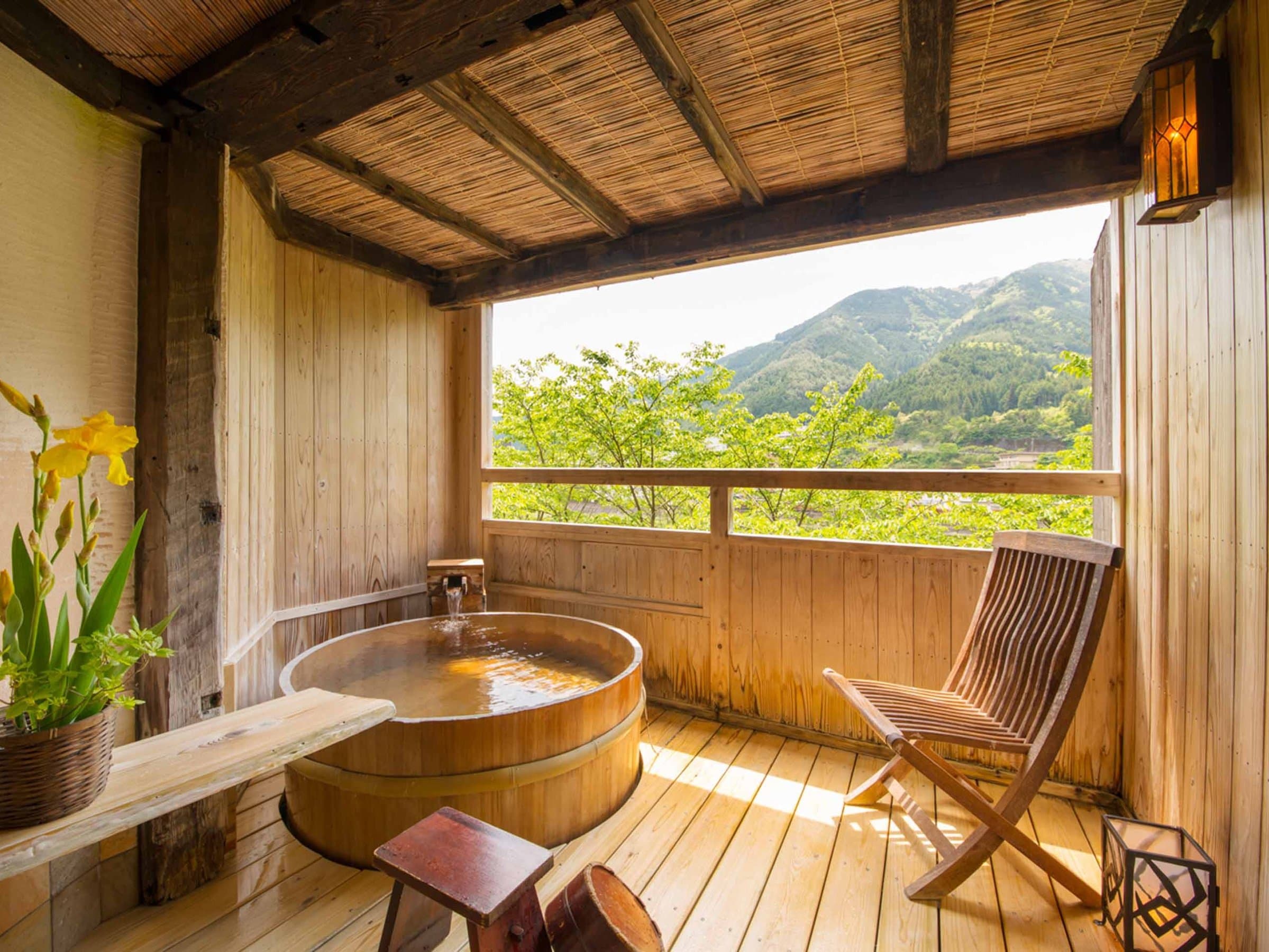 Round cypress soaking tub on a sunlit terrace facing forested hills, Yamagataya, Gero Onsen