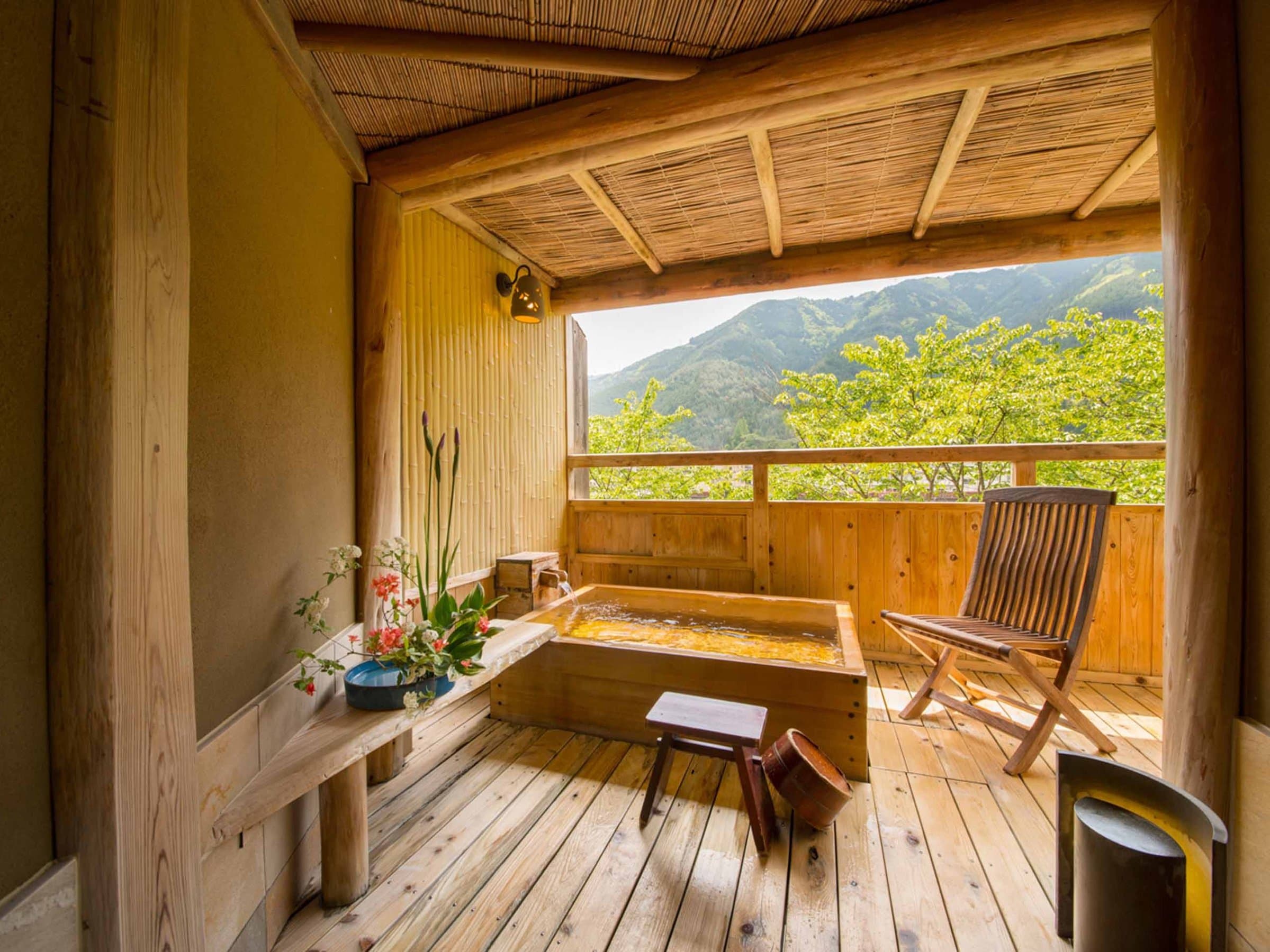 Guest-room private wooden bath under a reed canopy framing green mountain scenery, Yamagataya, Gero Onsen