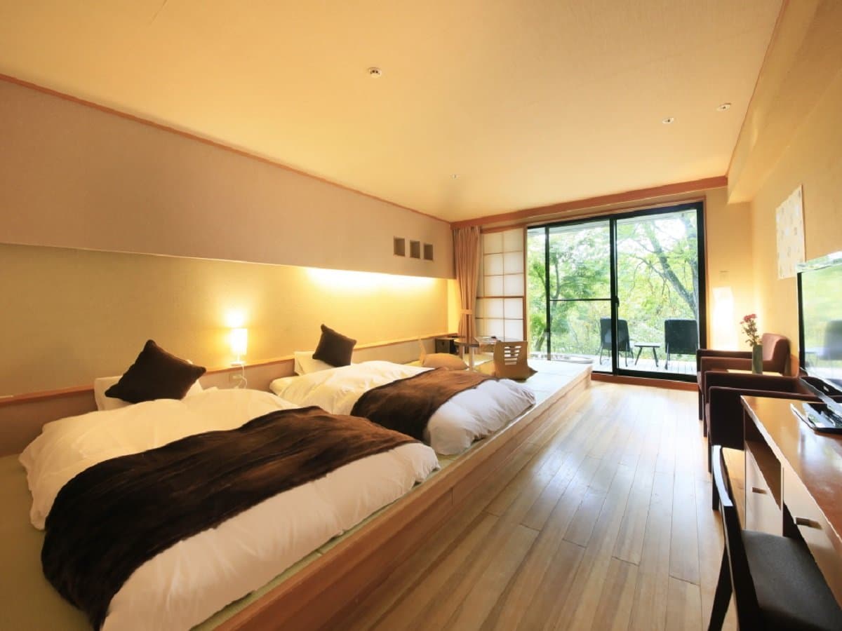 Twin-bed guest room with warm lighting and forest-view terrace at Okunikko Hotel Shikisai in Nikko