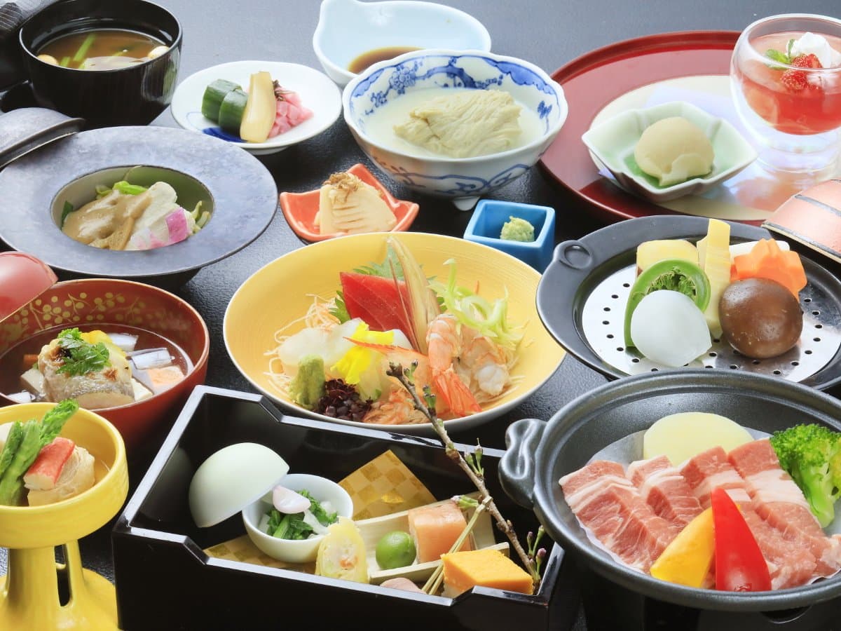 Multi-course kaiseki dinner spread with sashimi, simmered dishes and pork at Okunikko Hotel Shikisai