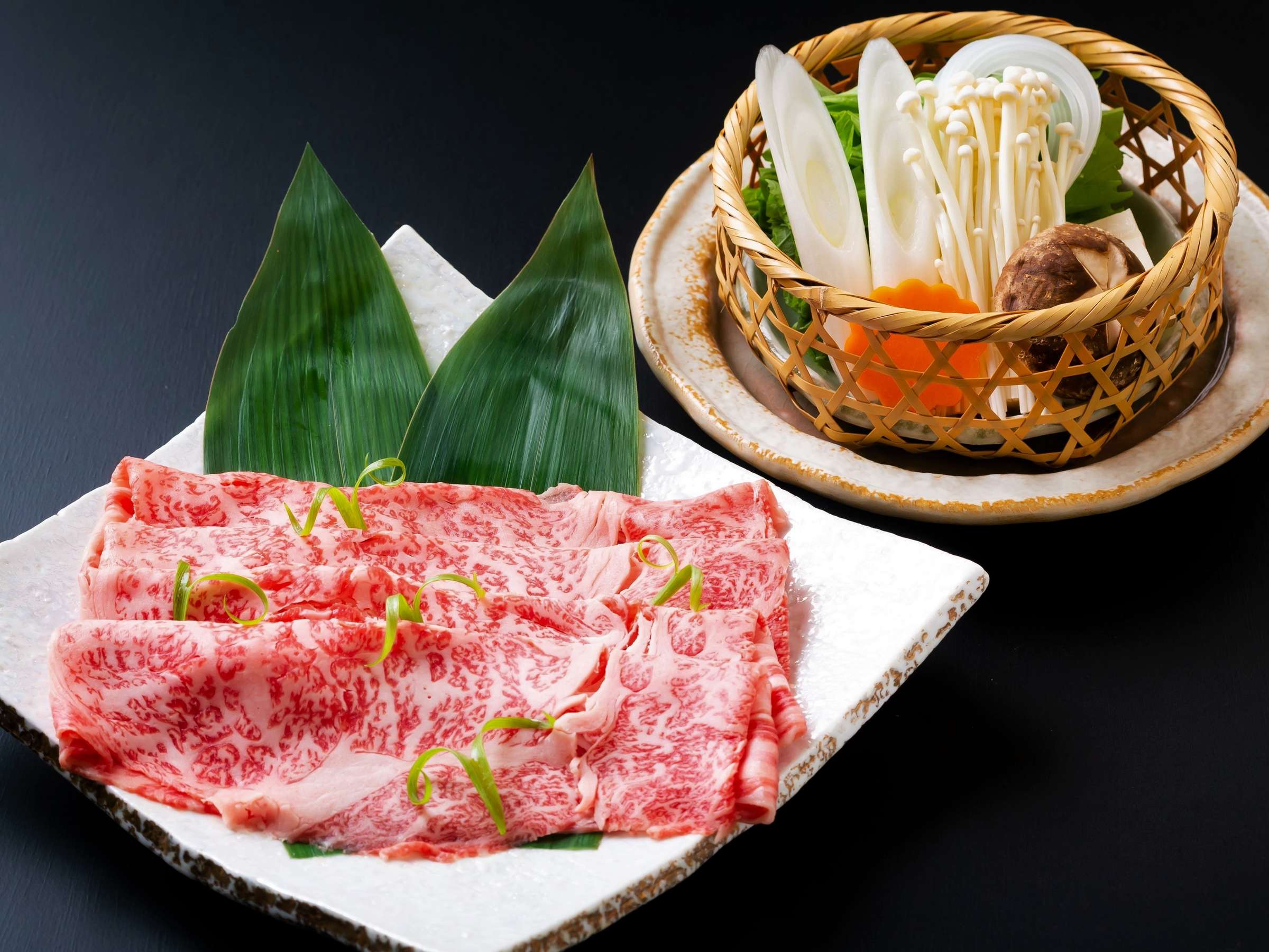 Marbled Oita wagyu beef slices plated beside a basket of fresh shabu-shabu vegetables, Kappo Ryokan Kannawa Bettei, Beppu Onsen