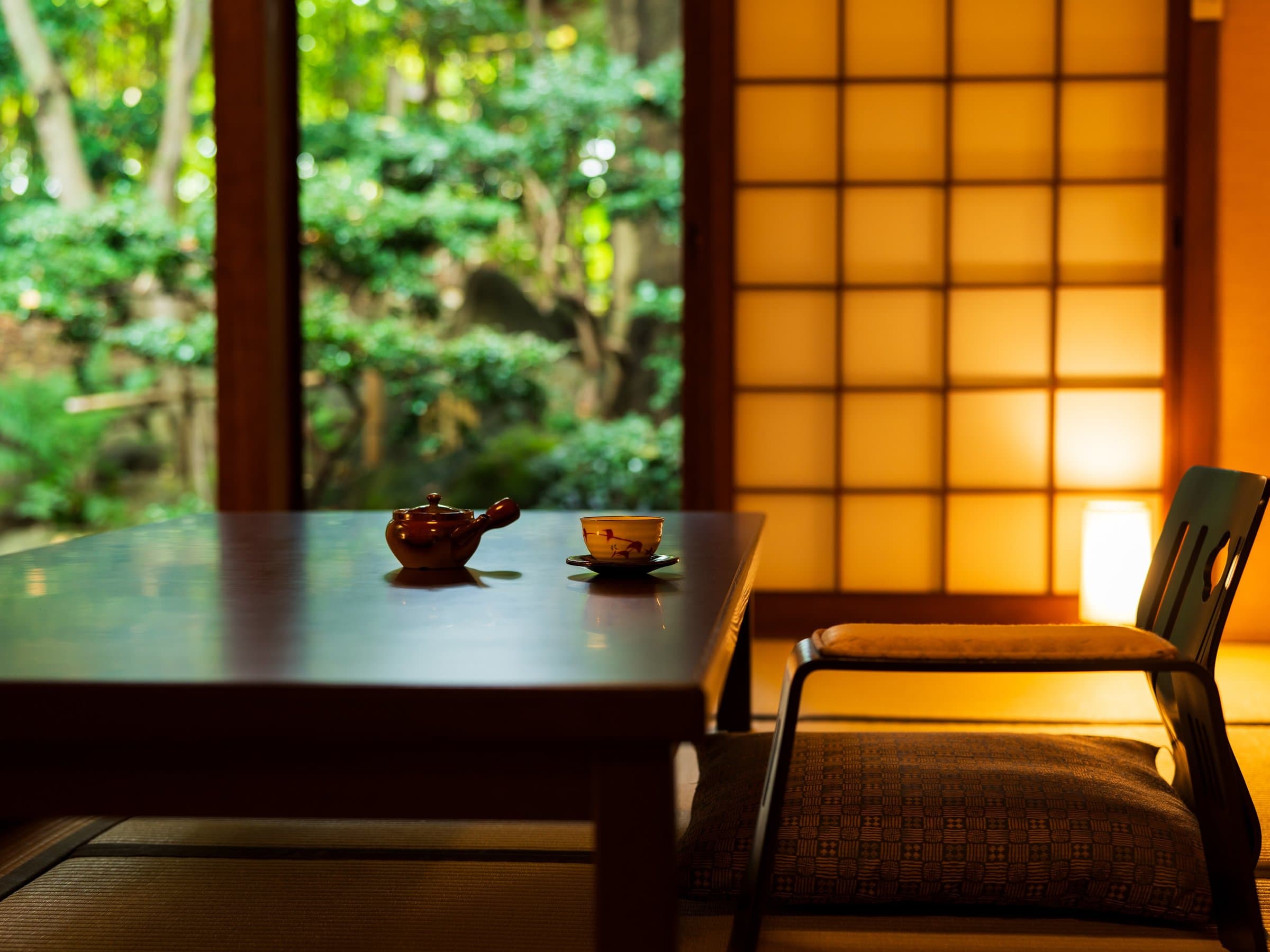 Tatami guest room with low table and teapot overlooking a green garden through a shoji-framed window, Kappo Ryokan Kannawa Bettei, Beppu Onsen